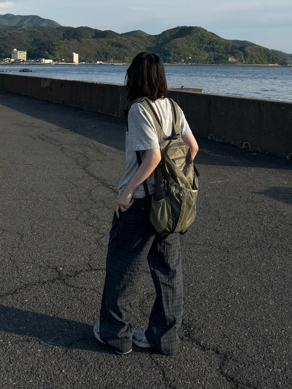 ブルー系のパンツ、シルバー系のスニーカー、グリーン系のバックパック/リュックを着用したレディースの春コーディネートの2枚目の写真