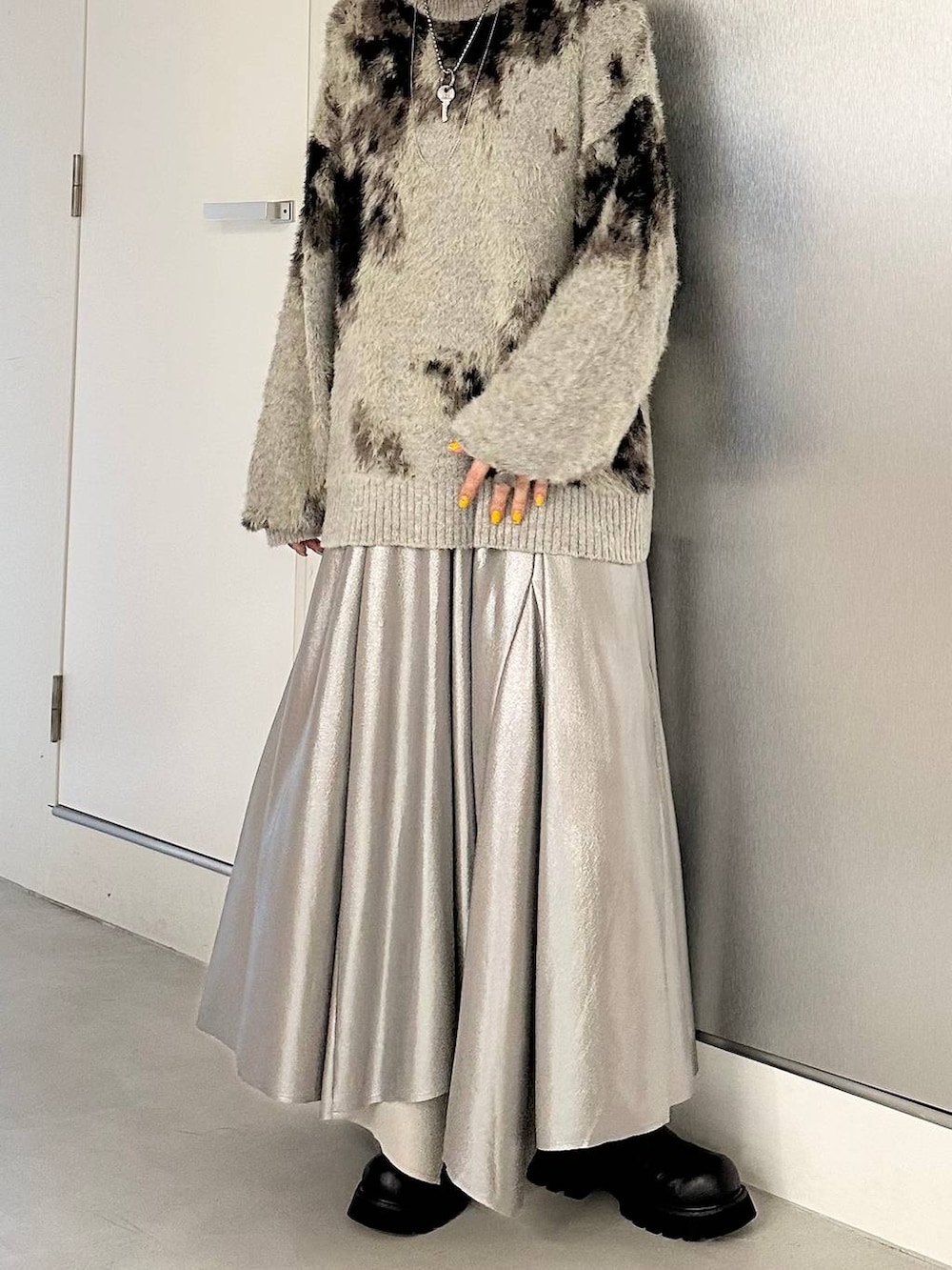 ブラック系のブーツ、グレー系のニット/セーター、シルバー系のスカートを着用したレディースの秋コーディネートの3枚目の写真