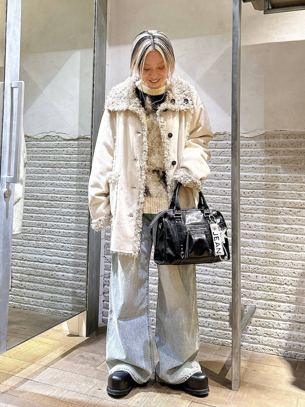 ブラウン系のニット/セーター、ブルー系のデニムパンツ、ブラック系のボストンバッグを着用したレディースの冬コーディネートの2枚目の写真