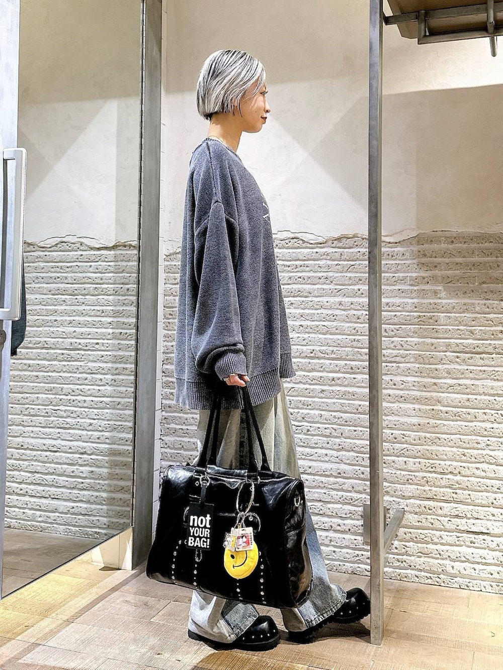 ブラック系のサンダル、ブルー系のデニムパンツ、ブラック系のトートバッグを着用したレディースの秋コーディネートの3枚目の写真