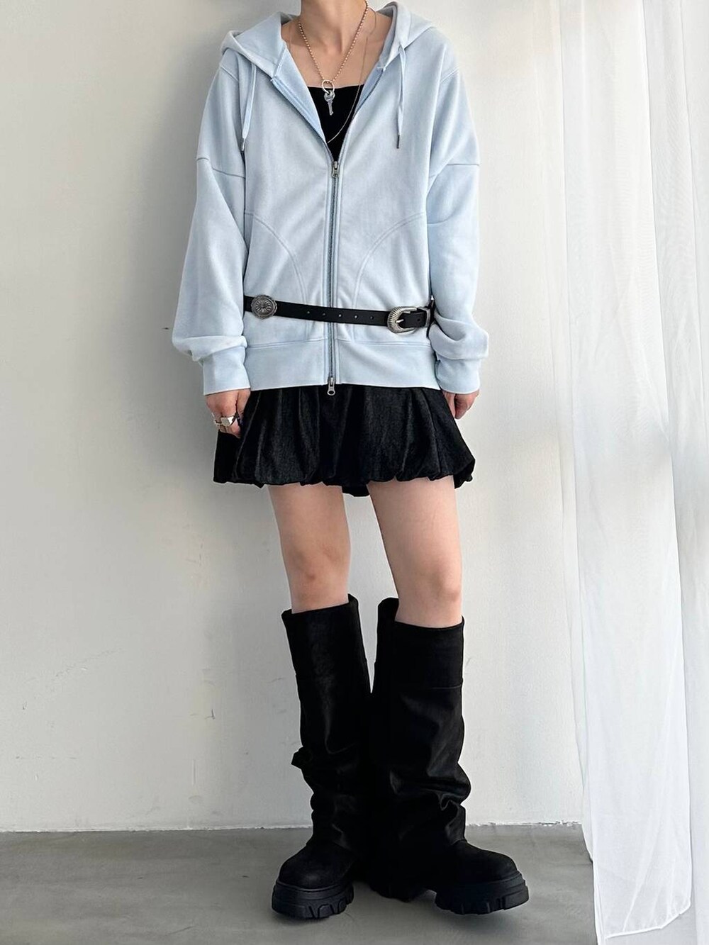 ブラック系のデニムスカート、ブラック系のブーツ、ブルー系のパーカーを着用したレディースの夏コーディネートの3枚目の写真