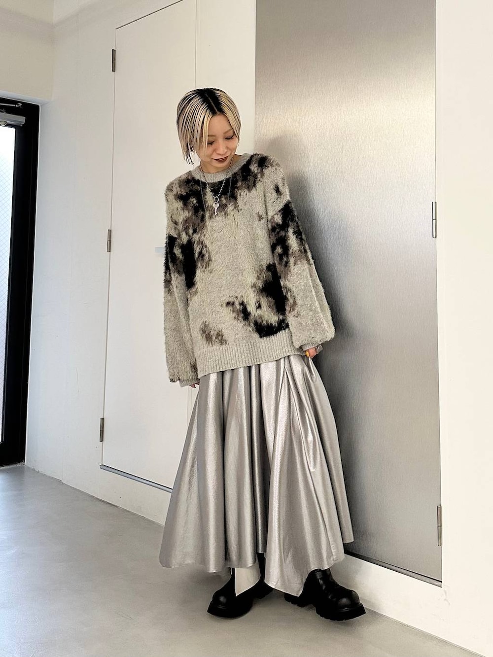 ブラック系のブーツ、グレー系のニット/セーター、シルバー系のスカートを着用したレディースの秋コーディネートの2枚目の写真