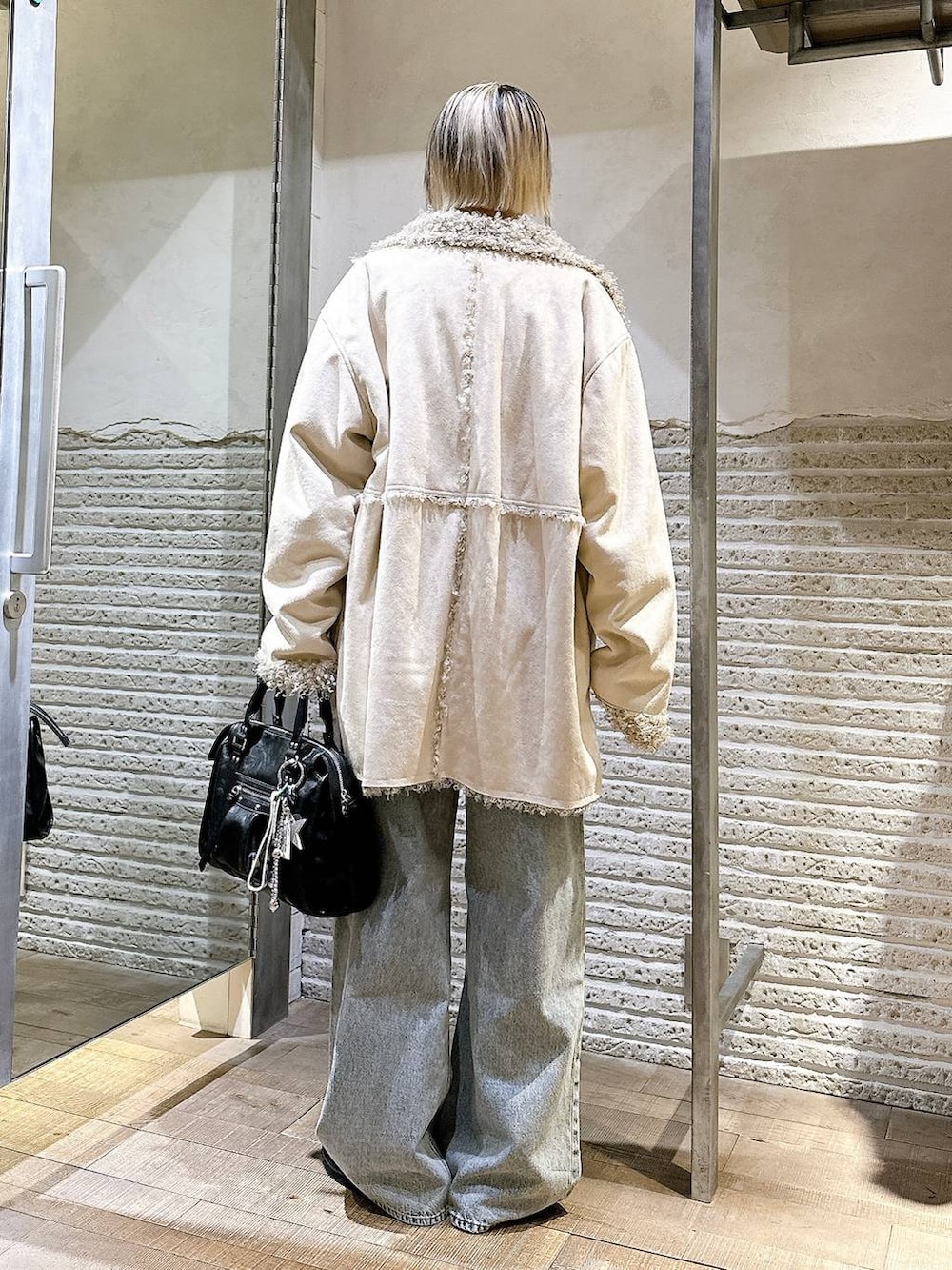 ブラウン系のニット/セーター、ブルー系のデニムパンツ、ブラック系のボストンバッグを着用したレディースの冬コーディネートの4枚目の写真