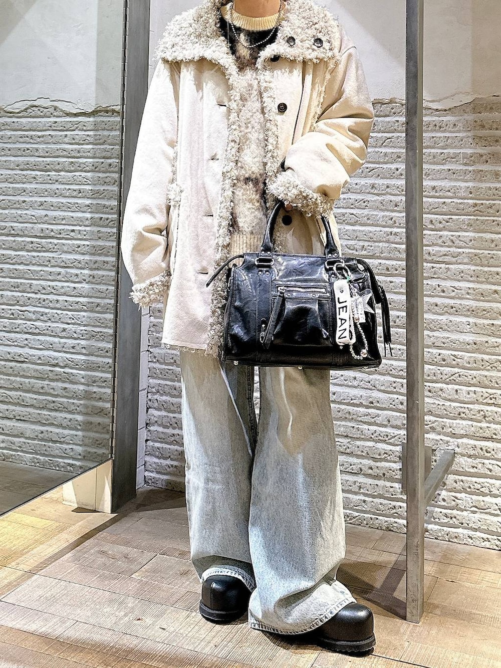 ブラウン系のニット/セーター、ブルー系のデニムパンツ、ブラック系のボストンバッグを着用したレディースの冬コーディネートの5枚目の写真