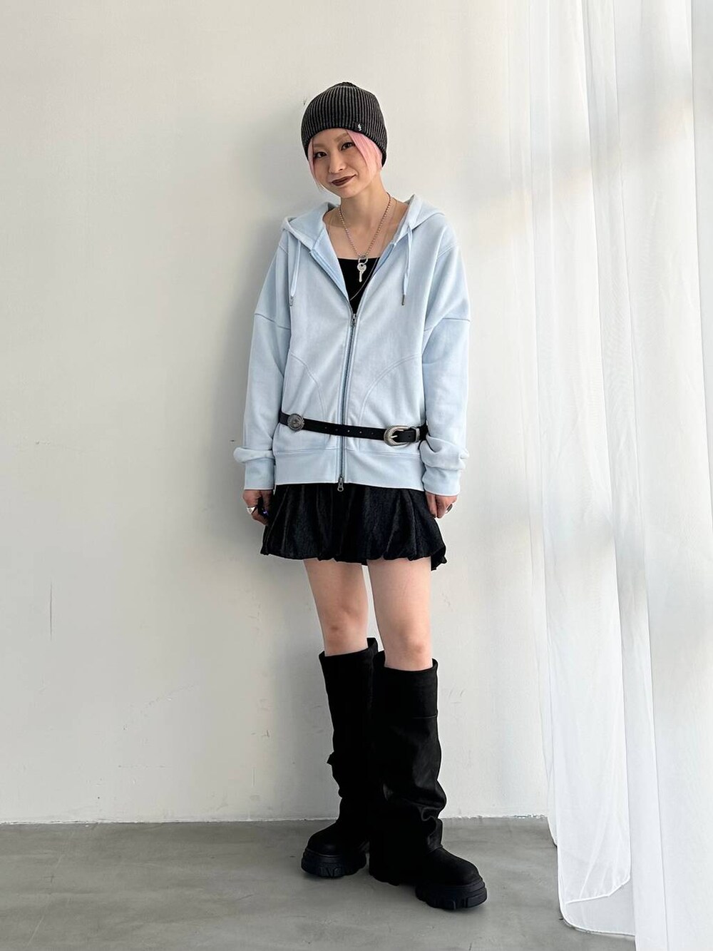 ブラック系のデニムスカート、ブラック系のブーツ、ブルー系のパーカーを着用したレディースの夏コーディネートの2枚目の写真