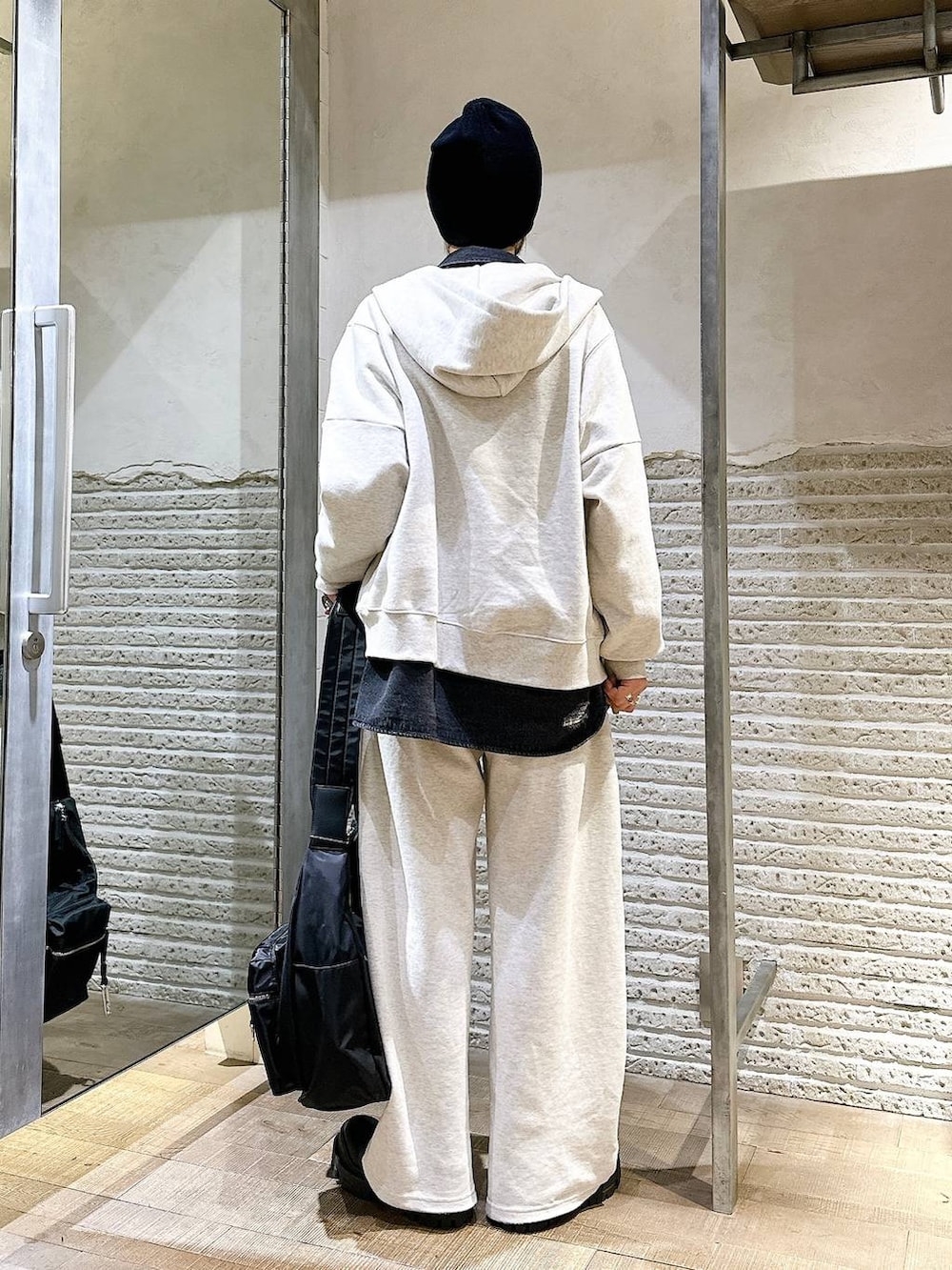 ブラック系のショルダーバッグ、ブラック系のブーツ、ベージュ系のスウェットパンツを着用したレディースの秋コーディネートの4枚目の写真