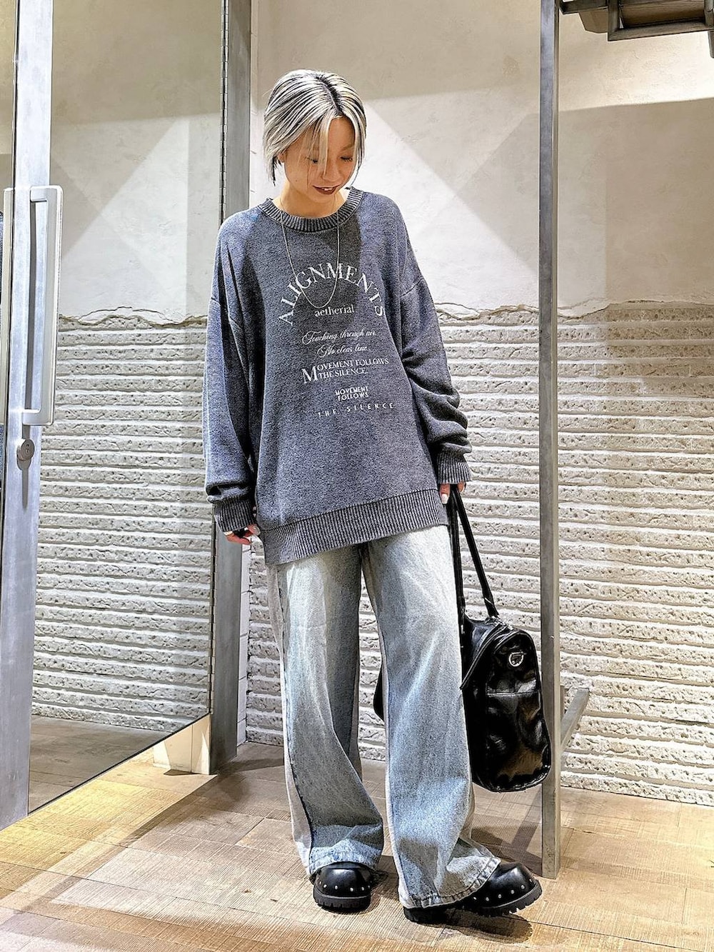 ブラック系のサンダル、ブルー系のデニムパンツ、ブラック系のトートバッグを着用したレディースの秋コーディネートの2枚目の写真