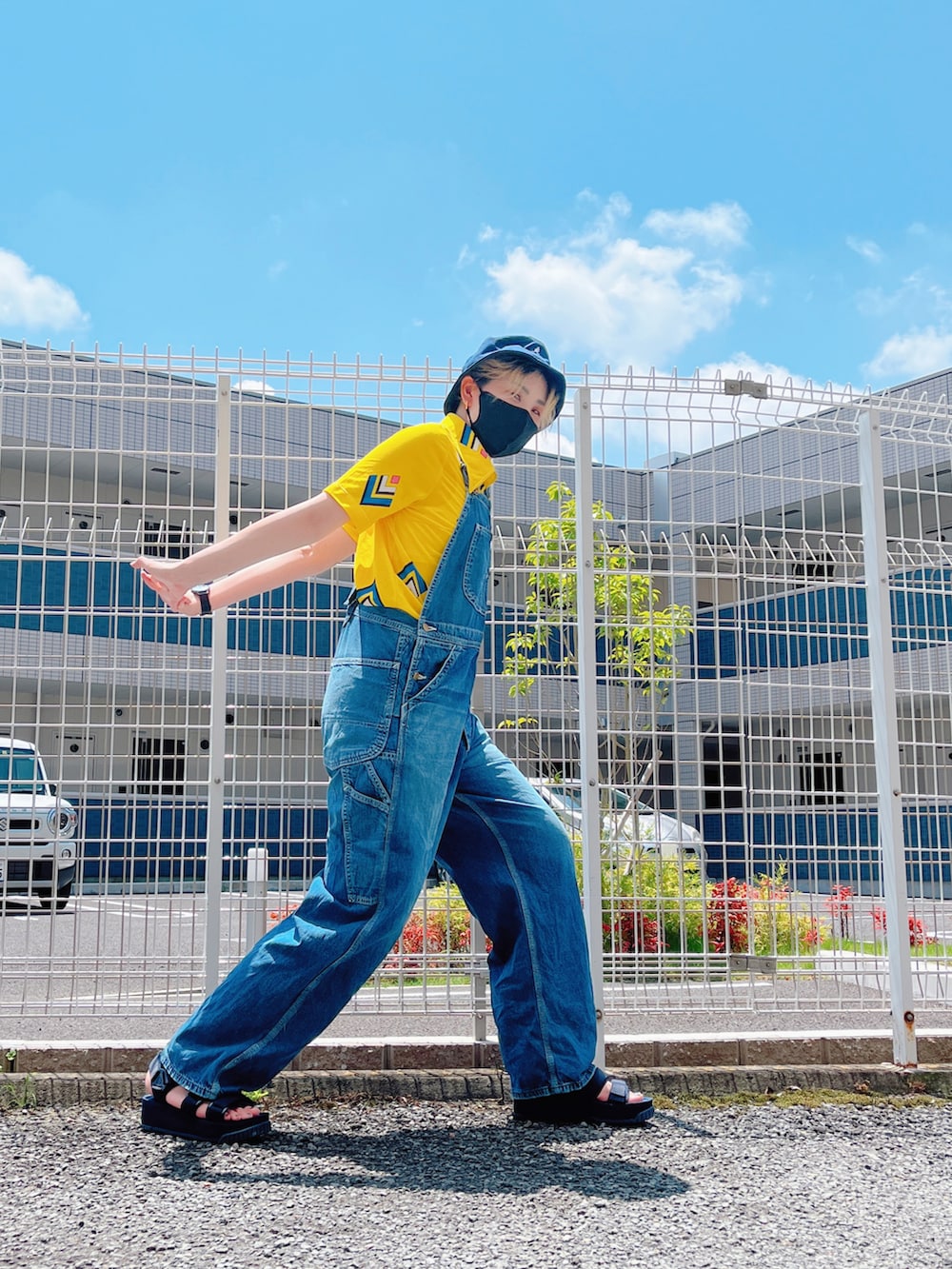 ブルー系のサロペット/オーバーオール、ブルー系のサンダル、イエロー系のシャツ/ブラウスを着用したレディースの夏コーディネートの2枚目の写真