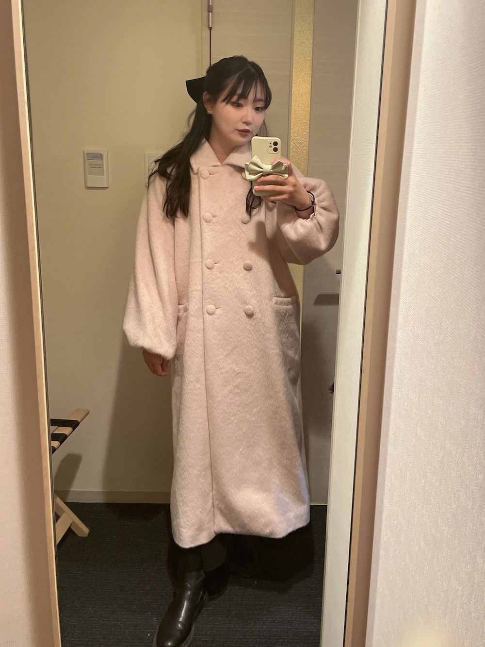 ピンク系のステンカラーコート、ブラック系のブーツ、ブラック系のバレッタ/ヘアクリップを着用したレディースの冬コーディネートの2枚目の写真