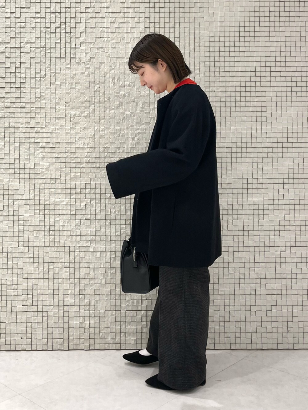 レッド系のニット/セーター、ブラック系のノーカラーコート、グレー系のその他パンツを着用したレディースの冬コーディネートの2枚目の写真