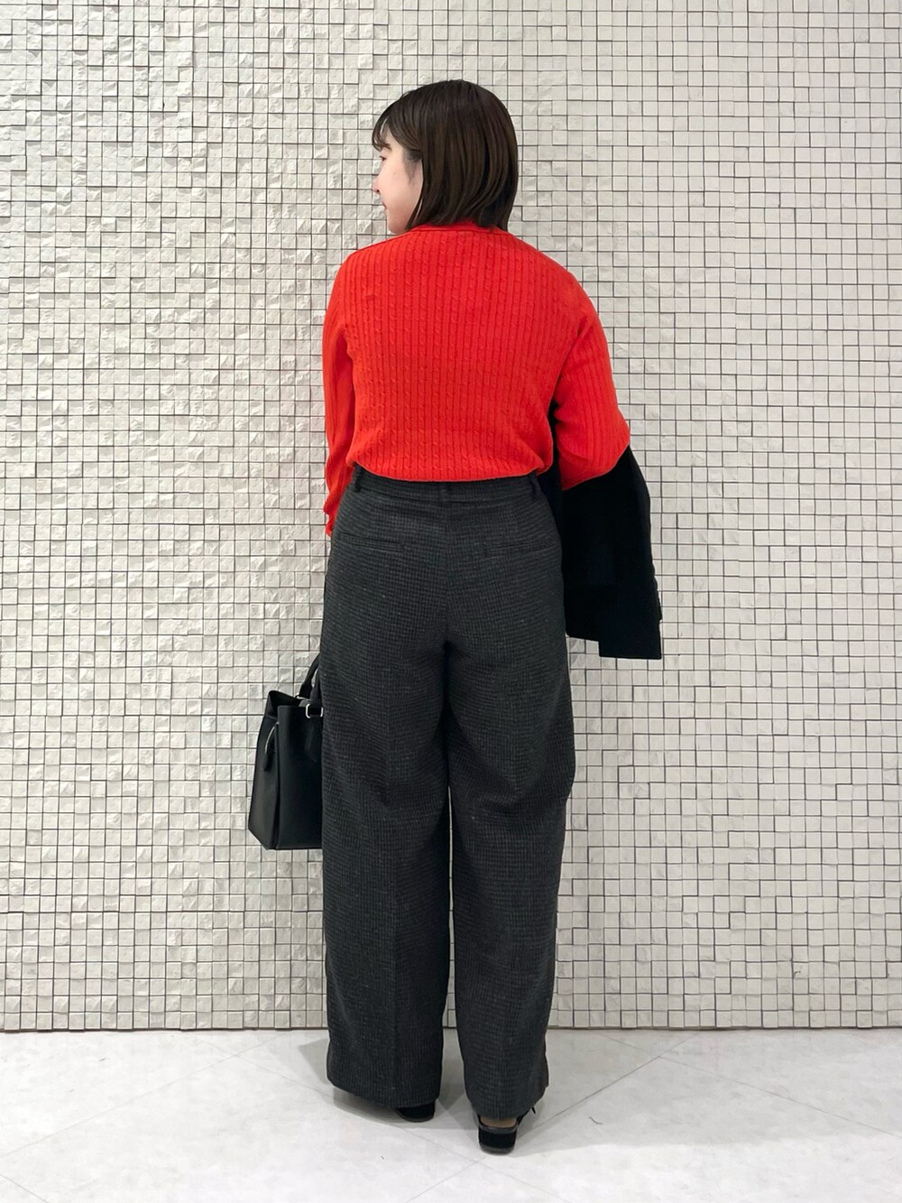 レッド系のニット/セーター、ブラック系のノーカラーコート、グレー系のその他パンツを着用したレディースの冬コーディネートの5枚目の写真