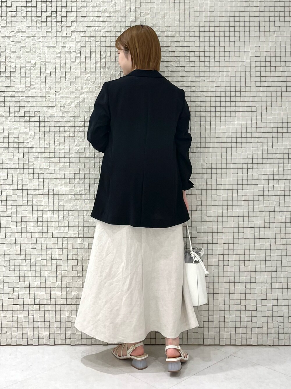 グレー系のTシャツ/カットソー、ベージュ系のスカート、ホワイト系のショルダーバッグを着用したレディースの夏コーディネートの3枚目の写真