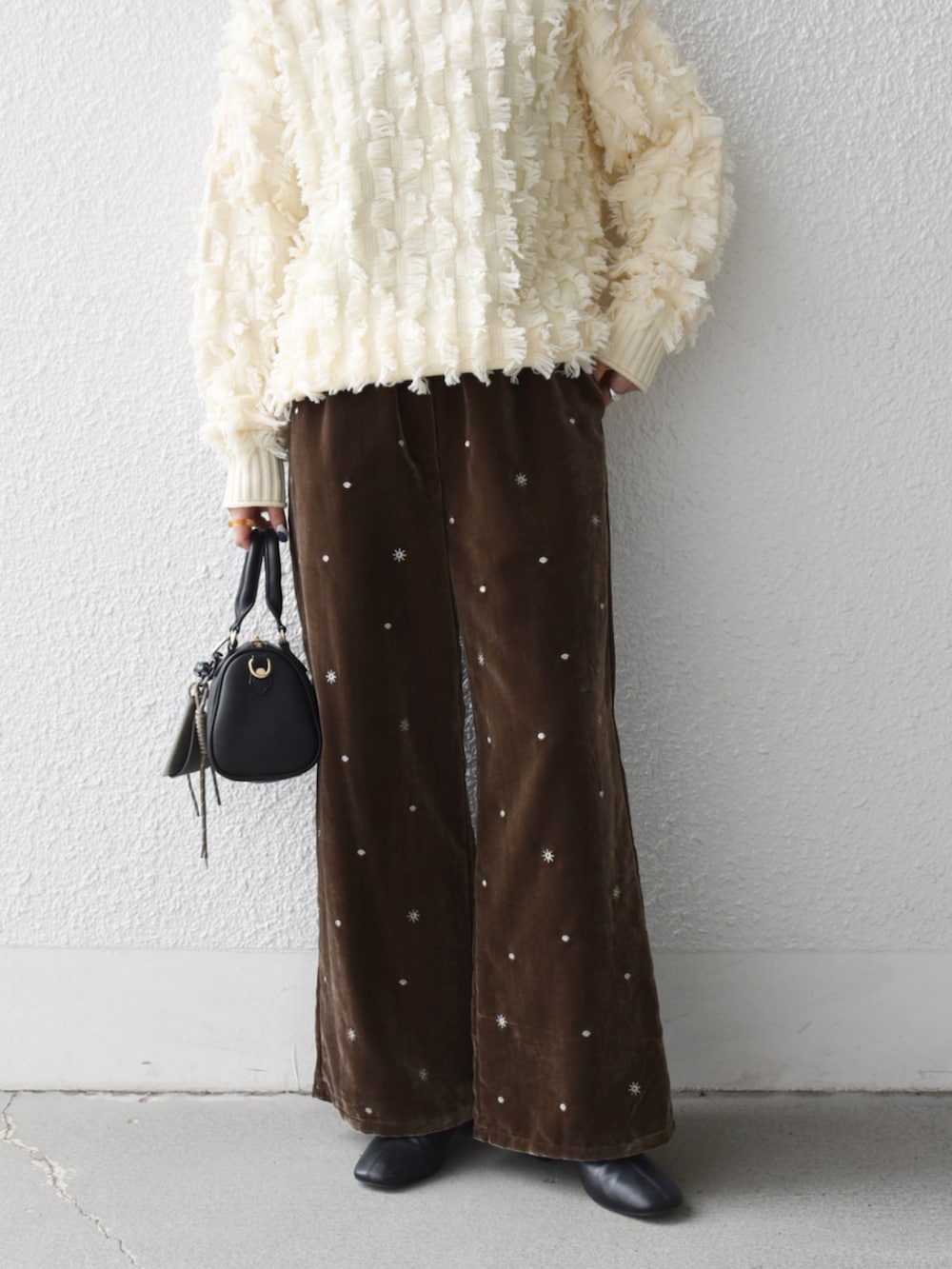 ブラック系のボストンバッグ、ホワイト系のニット/セーター、ブラウン系のその他パンツを着用したレディースの冬コーディネートの2枚目の写真