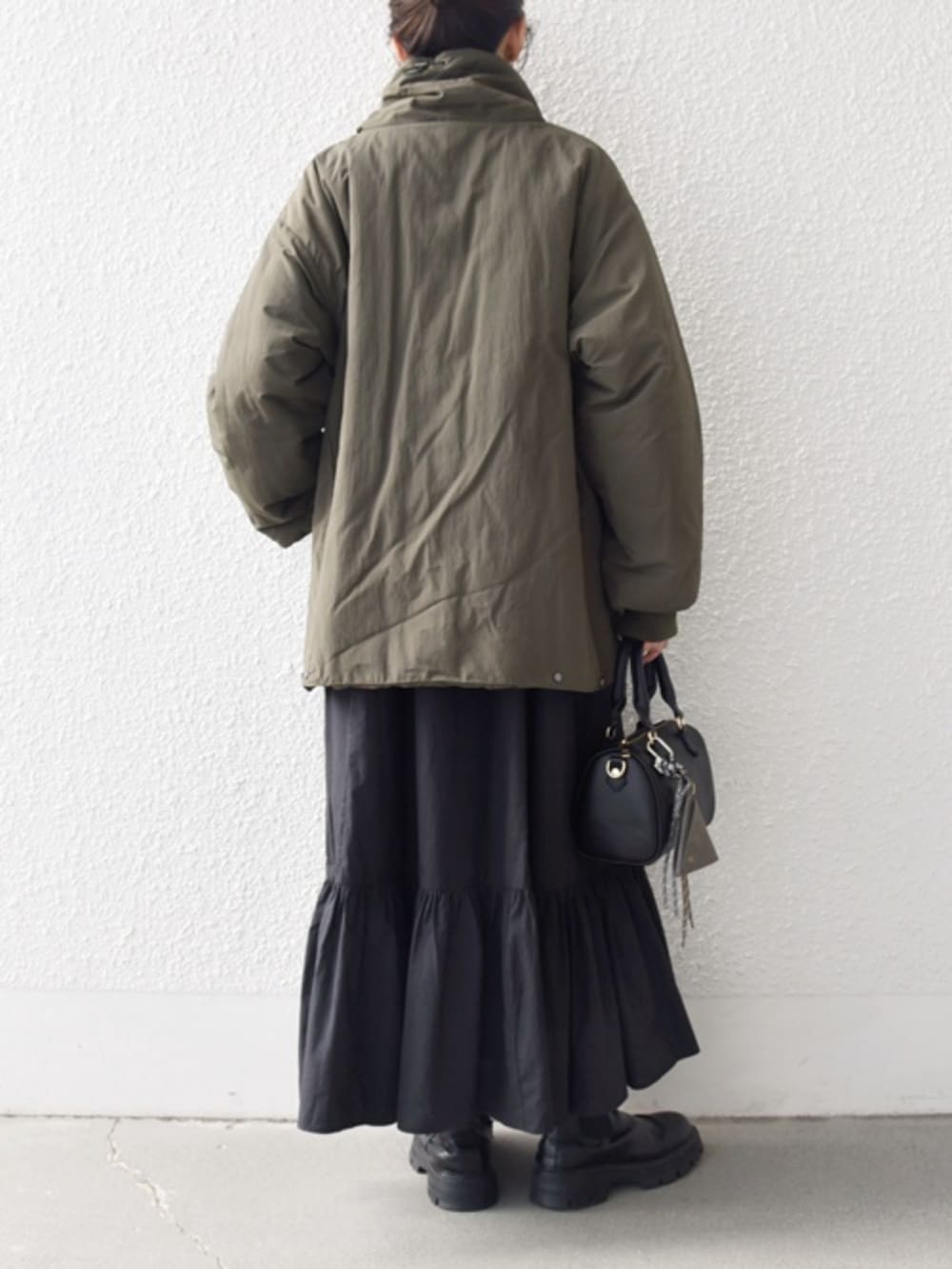 ブラック系のブーツ、ブラック系のボストンバッグ、グリーン系のブルゾンを着用したレディースの冬コーディネートの2枚目の写真