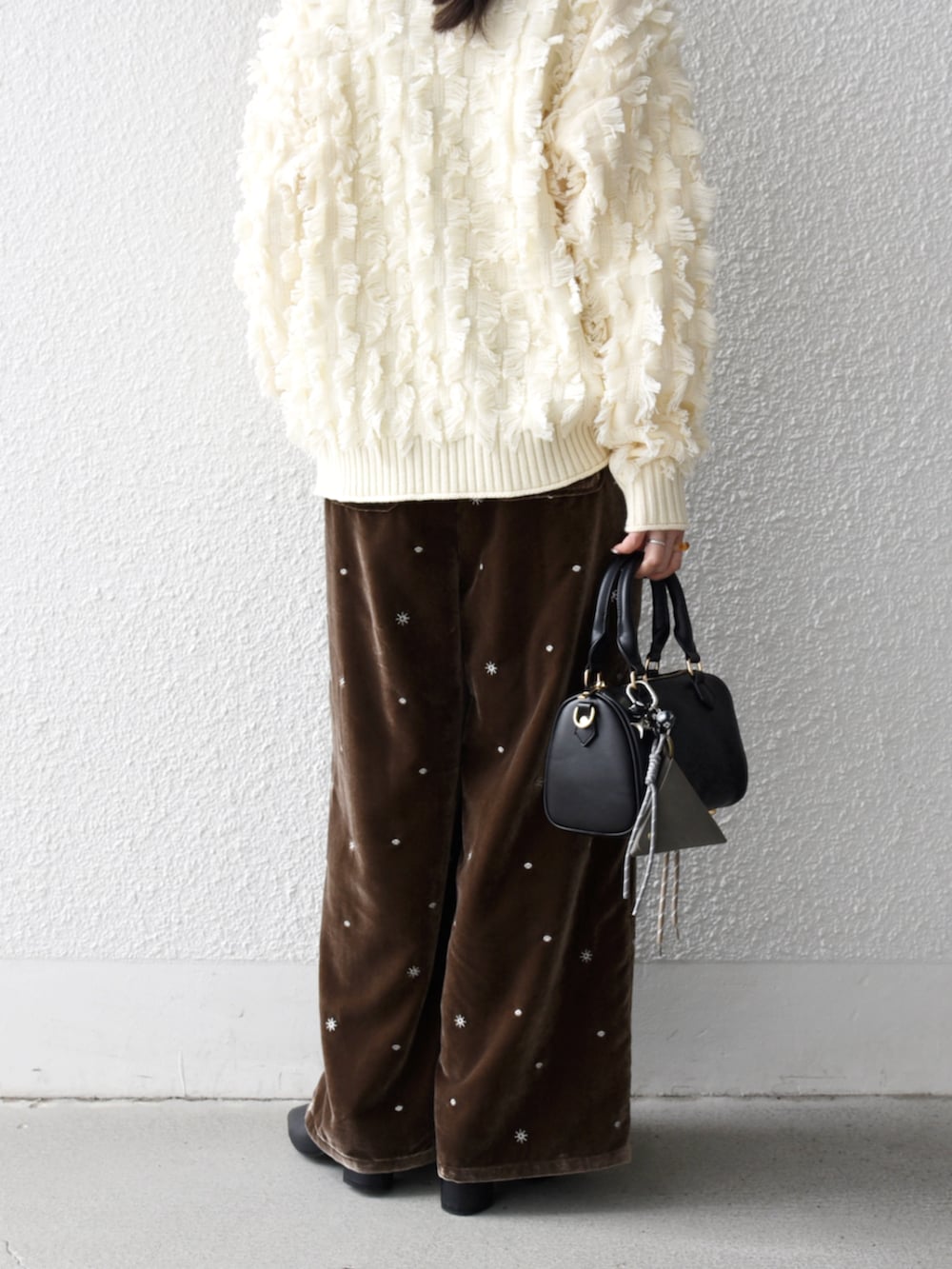 ブラック系のボストンバッグ、ホワイト系のニット/セーター、ブラウン系のその他パンツを着用したレディースの冬コーディネートの3枚目の写真