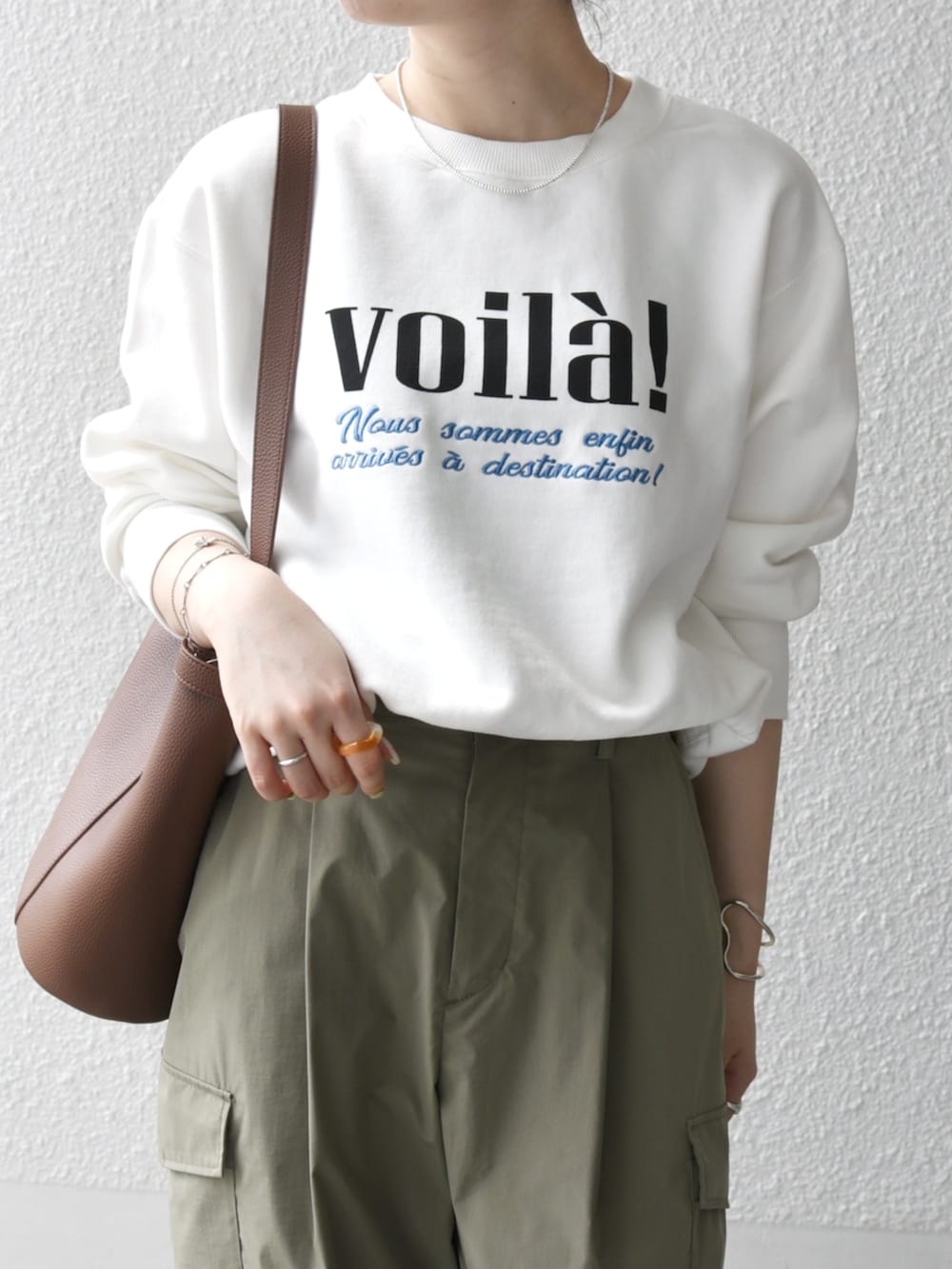 グリーン系のカーゴパンツ、ブラウン系のショルダーバッグ、ホワイト系のスウェットを着用したレディースの秋コーディネートの2枚目の写真