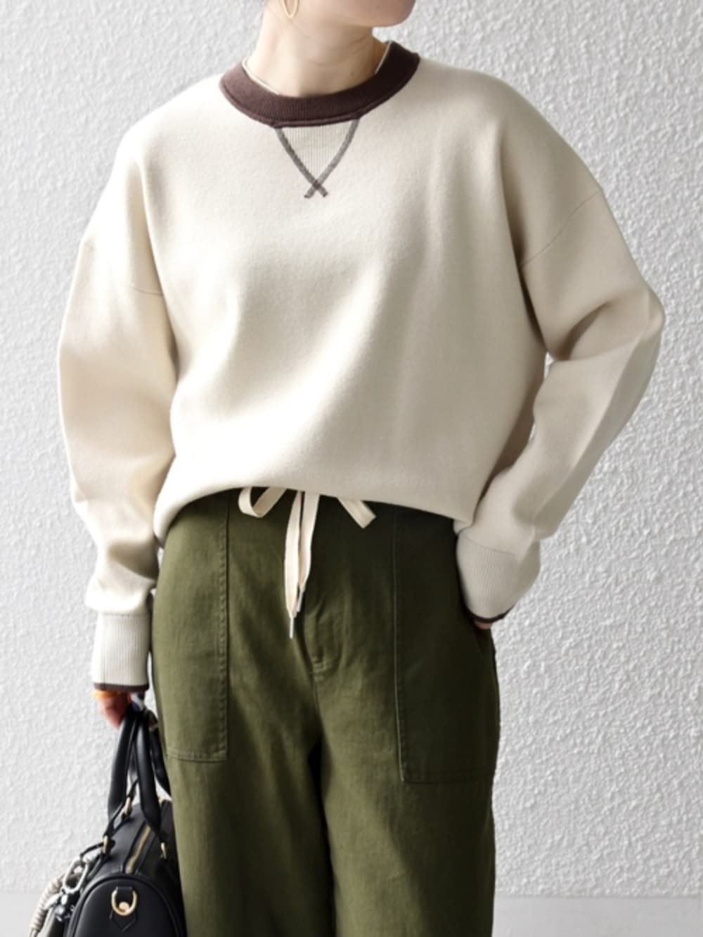 ベージュ系のニット/セーター、グリーン系のその他パンツ、グレー系のキーケース/キーアクセサリーを着用したレディースの冬コーディネートの2枚目の写真