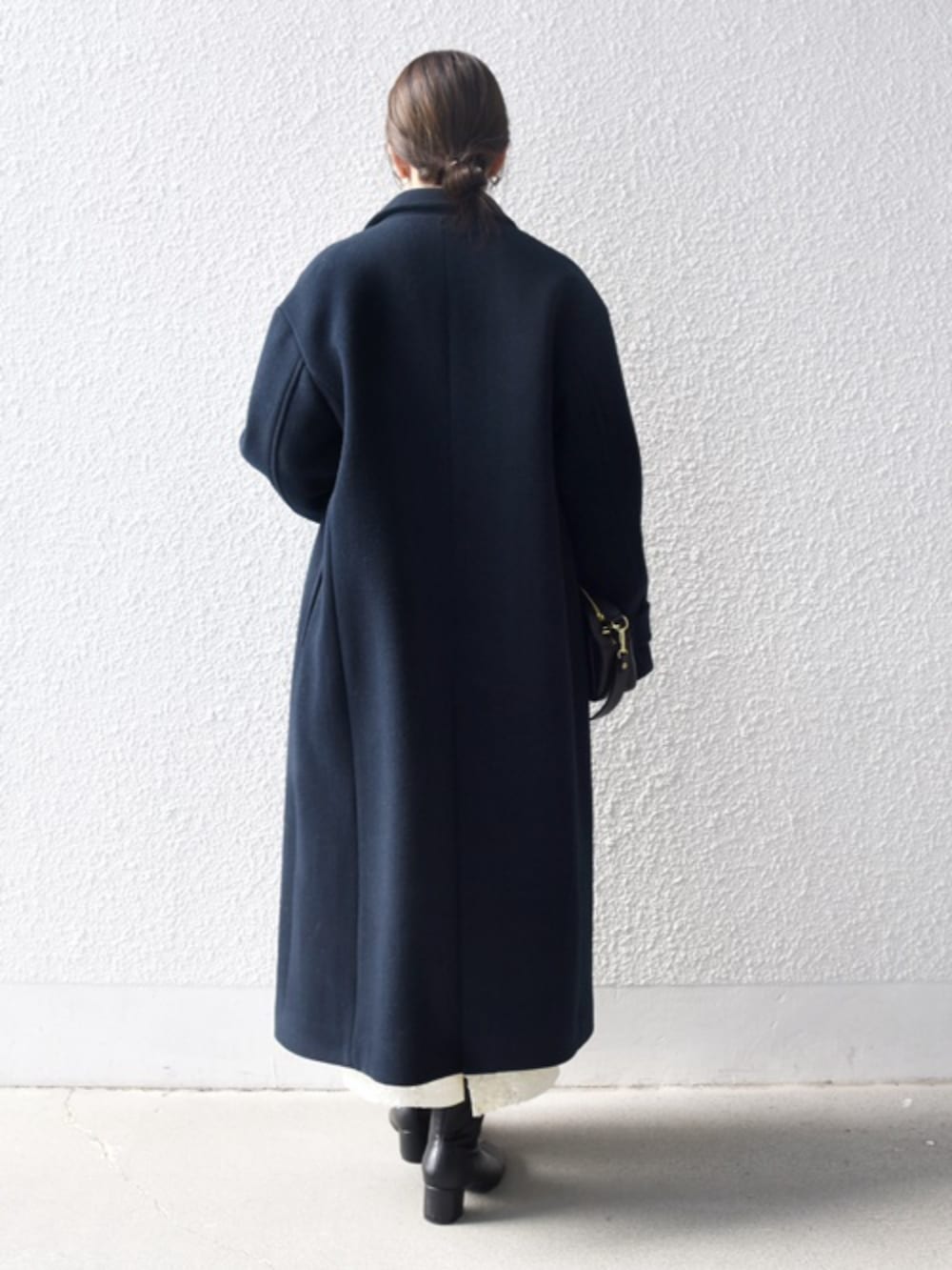 ブルー系のチェスターコート、グレー系のカーディガン/ボレロ、ベージュ系のスカートを着用したレディースの秋コーディネートの2枚目の写真