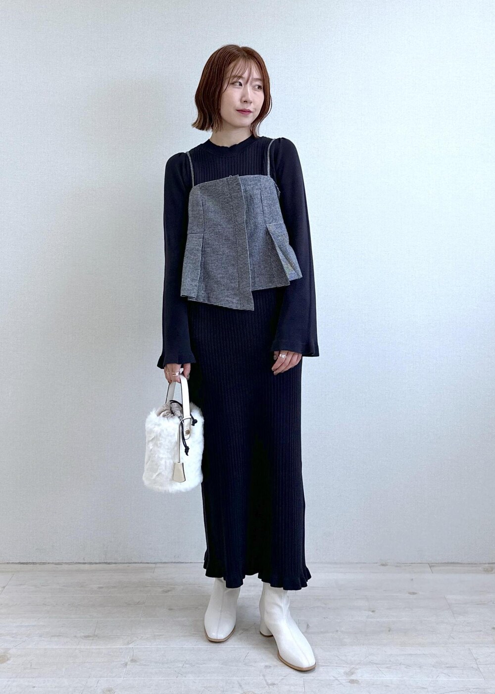 ホワイト系のショルダーバッグ、ホワイト系のブーツ、ブラック系のワンピースを着用したレディースの秋コーディネートの2枚目の写真