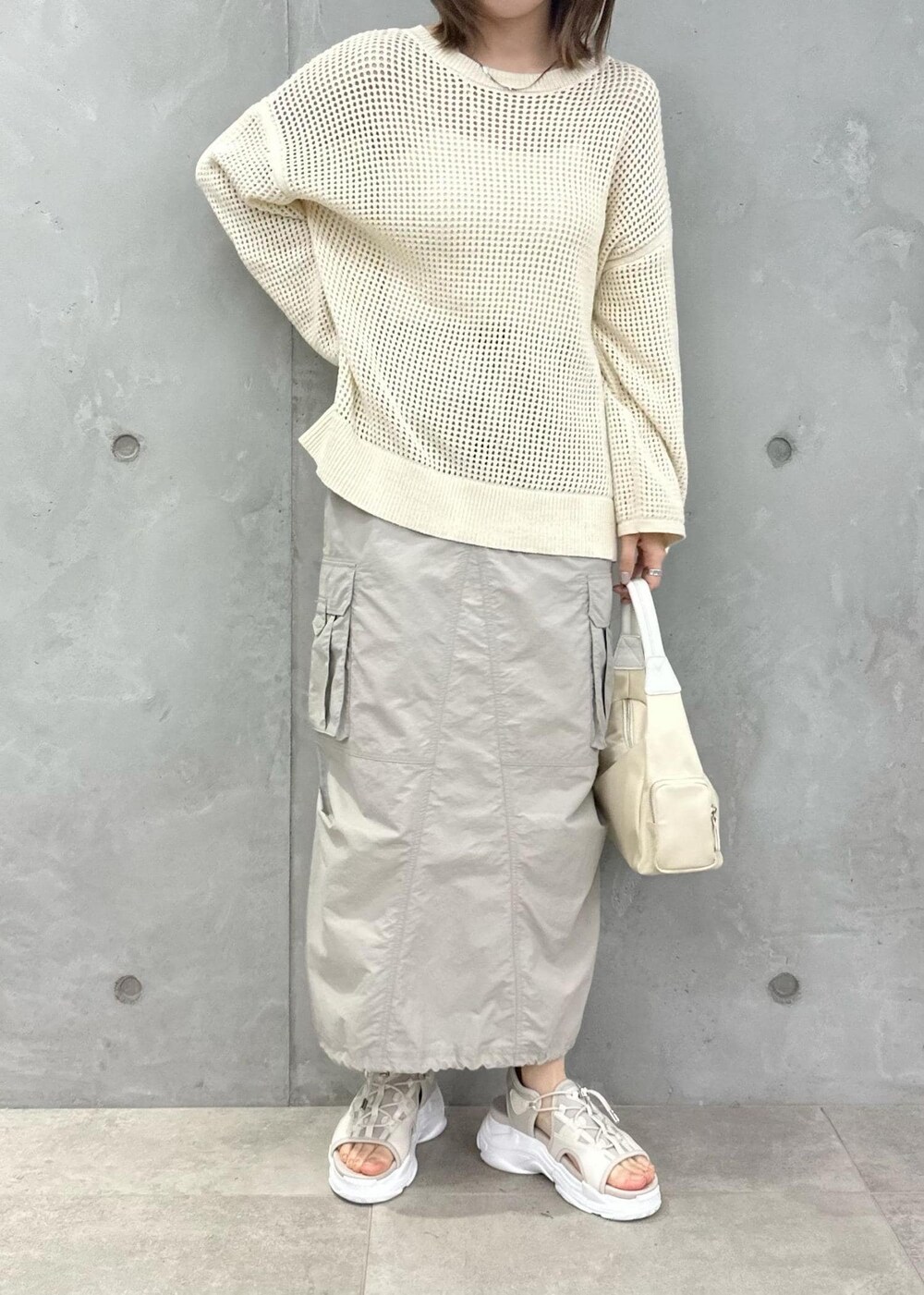 ホワイト系のハンドバッグ、ベージュ系のスカート、ホワイト系のニット/セーターを着用したレディースの春コーディネートの3枚目の写真