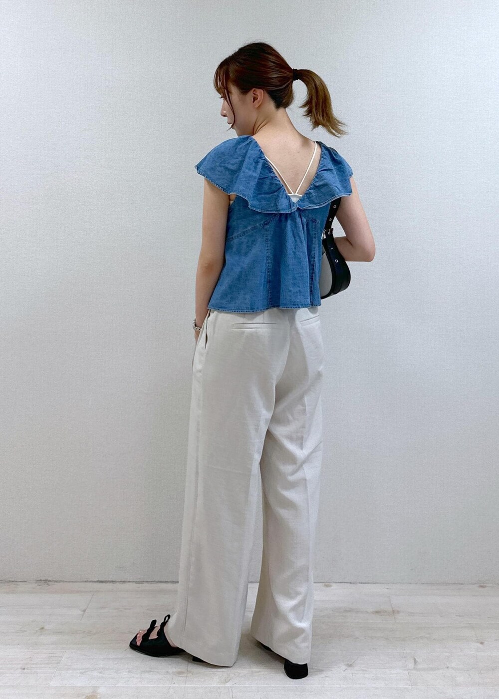 ブラック系のサンダル、ホワイト系のスラックス、ブラック系のショルダーバッグを着用したレディースの夏コーディネートの3枚目の写真