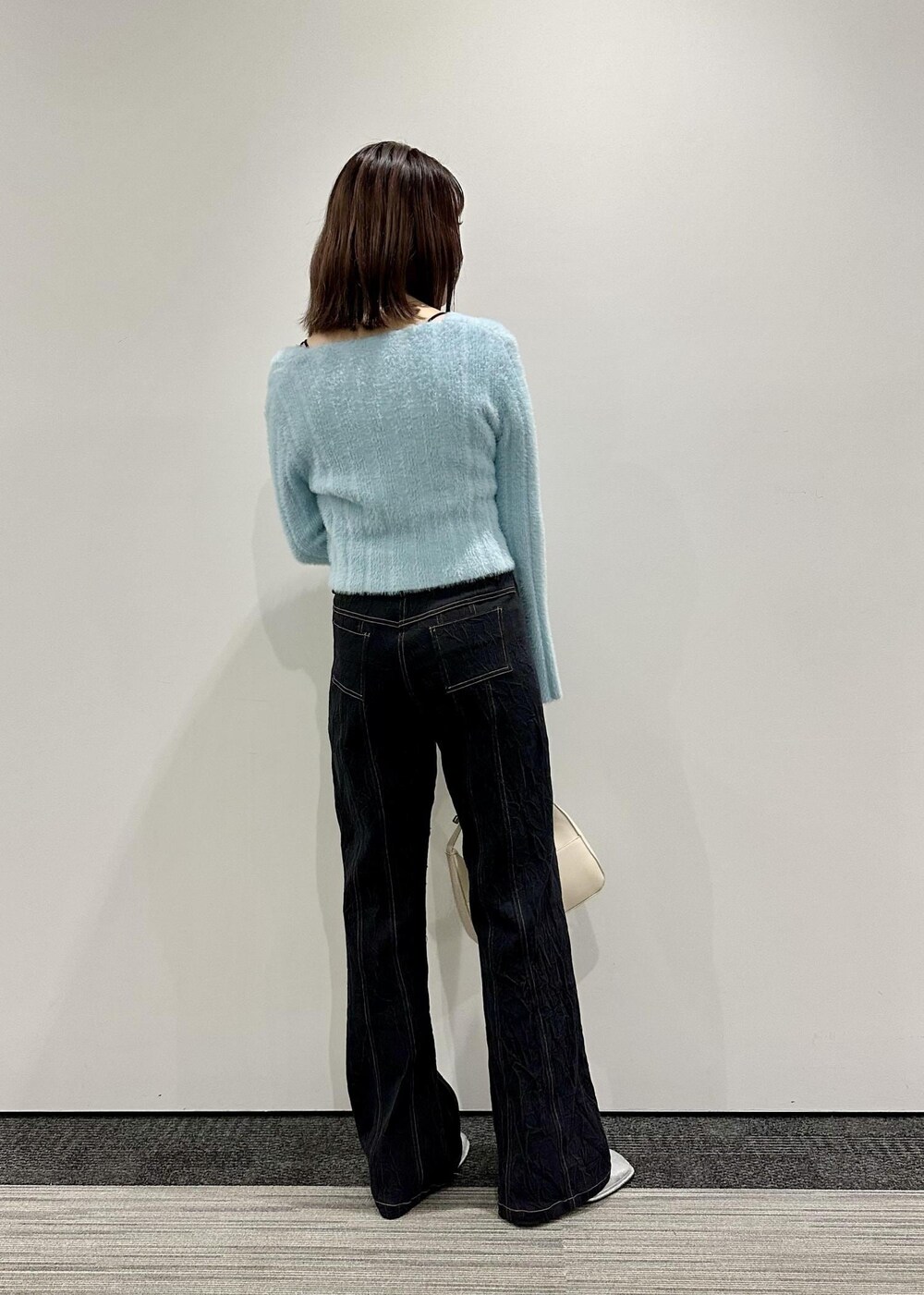 ホワイト系のハンドバッグ、シルバー系のその他シューズ、ブルー系のニット/セーターを着用したレディースの冬コーディネートの2枚目の写真