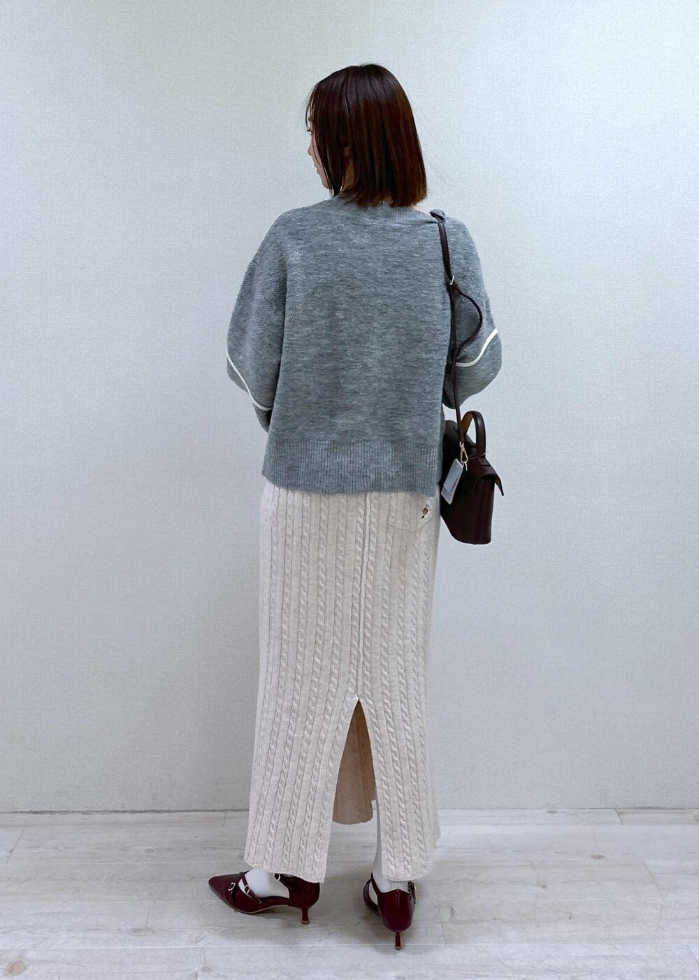 レッド系のパンプス、グレー系のニット/セーター、ブラウン系のショルダーバッグを着用したレディースの冬コーディネートの2枚目の写真