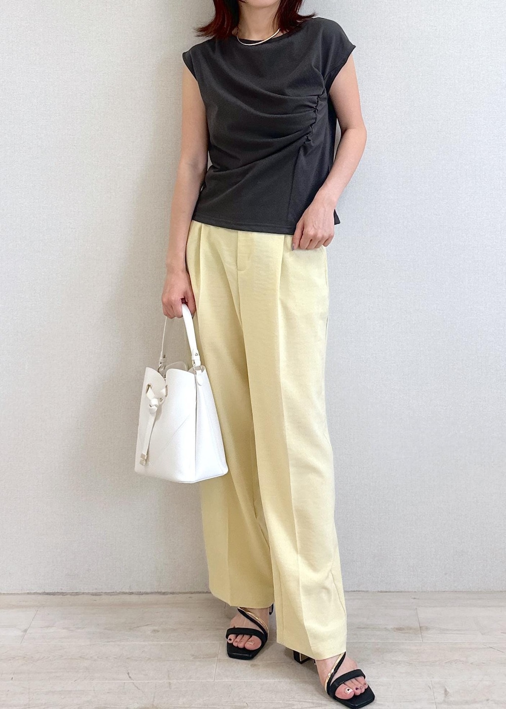 ホワイト系のショルダーバッグ、ブラック系のサンダル、イエロー系のスラックスを着用したレディースの夏コーディネートの4枚目の写真