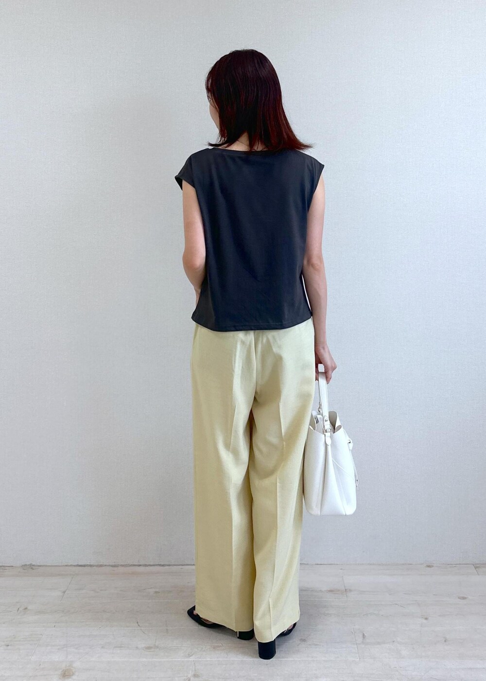 ホワイト系のショルダーバッグ、ブラック系のサンダル、イエロー系のスラックスを着用したレディースの夏コーディネートの3枚目の写真