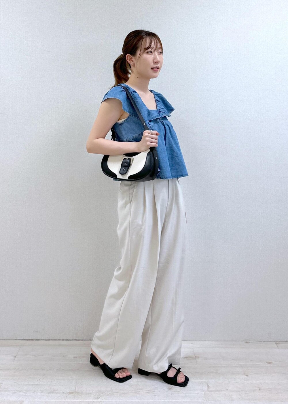ブラック系のサンダル、ホワイト系のスラックス、ブラック系のショルダーバッグを着用したレディースの夏コーディネートの2枚目の写真