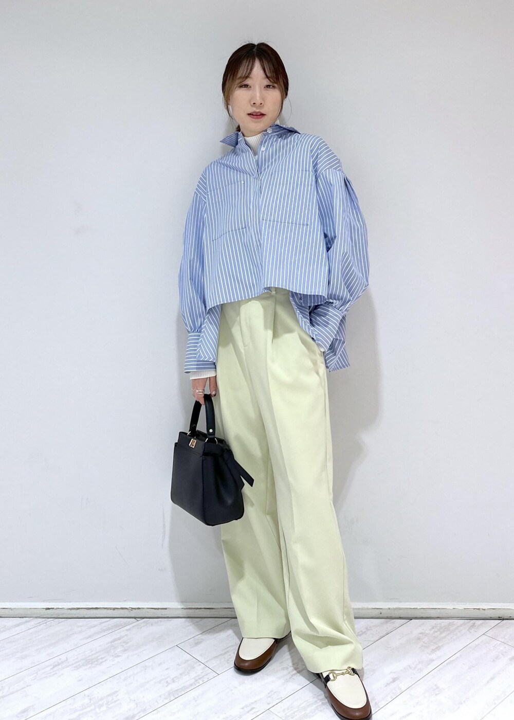 ブラウン系のローファー、ブラック系のハンドバッグ、ホワイト系のニット/セーターを着用したレディースの冬コーディネートの2枚目の写真