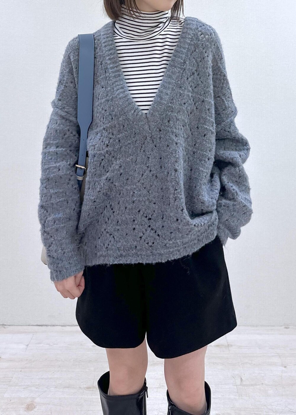 ベージュ系のショルダーバッグ、ブルー系のニット/セーター、ホワイト系のTシャツ/カットソーを着用したレディースの冬コーディネートの5枚目の写真