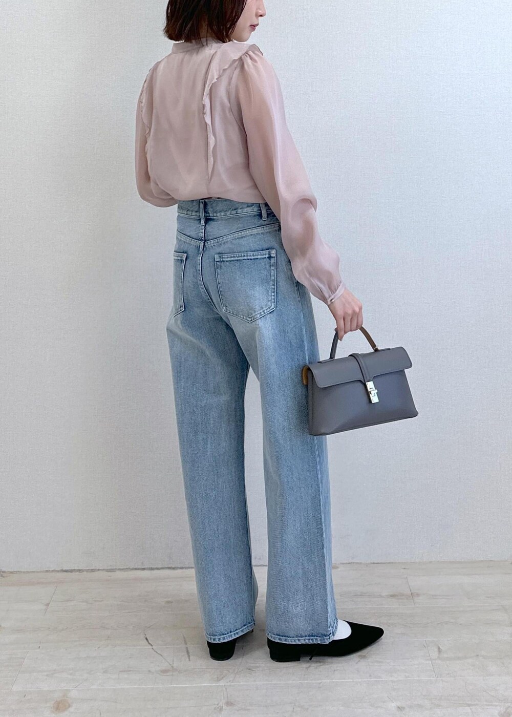 ブルー系のデニムパンツ、ブラック系のパンプス、グレー系のショルダーバッグを着用したレディースの春コーディネートの3枚目の写真