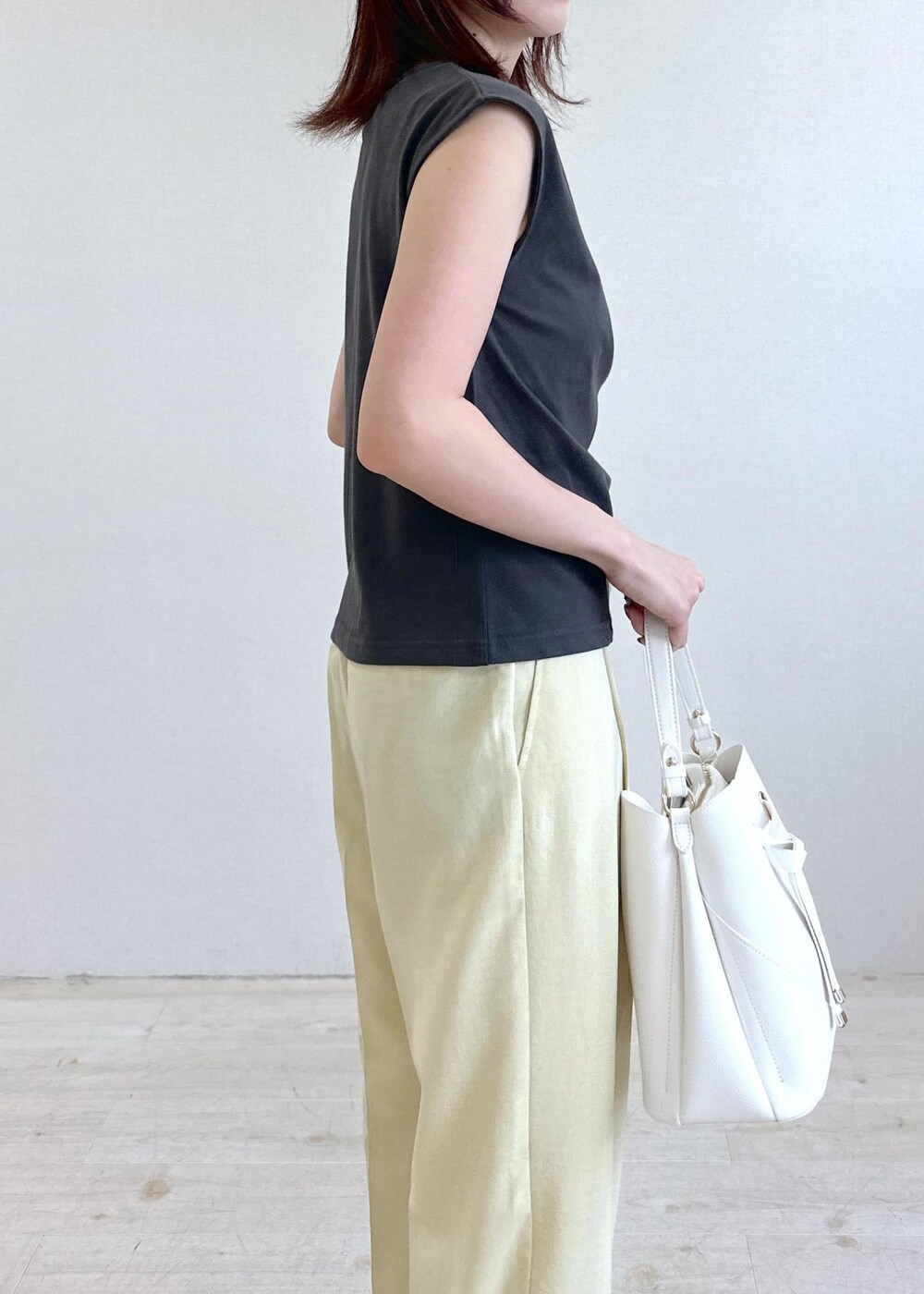ホワイト系のショルダーバッグ、ブラック系のサンダル、イエロー系のスラックスを着用したレディースの夏コーディネートの6枚目の写真