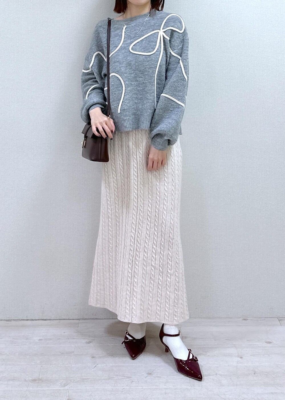 レッド系のパンプス、グレー系のニット/セーター、ブラウン系のショルダーバッグを着用したレディースの冬コーディネートの4枚目の写真