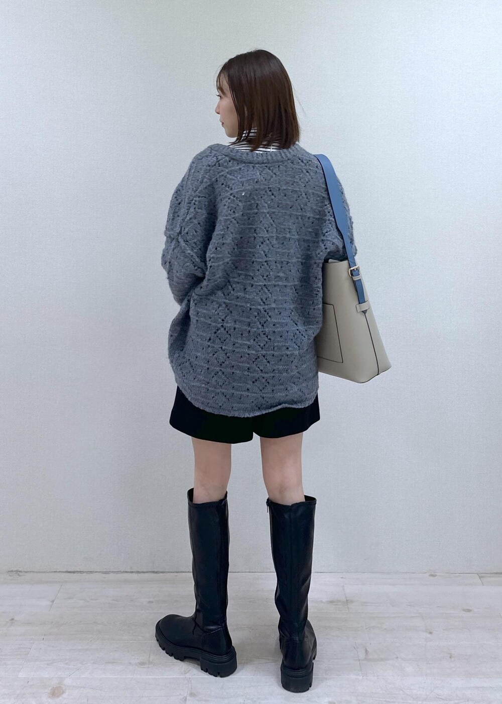 ベージュ系のショルダーバッグ、ブルー系のニット/セーター、ホワイト系のTシャツ/カットソーを着用したレディースの冬コーディネートの2枚目の写真