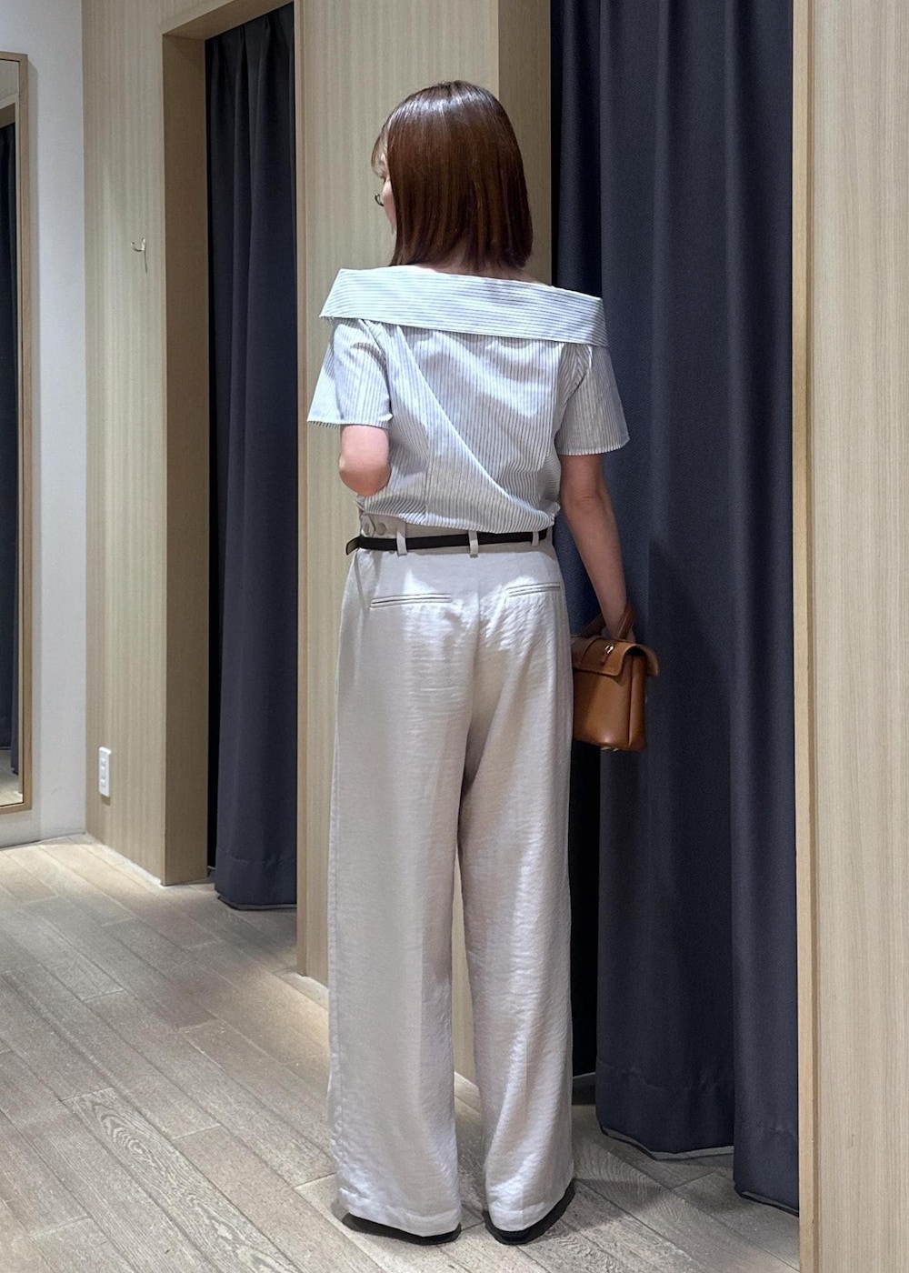 イエロー系のショルダーバッグ、ブラック系のパンプス、ホワイト系のその他パンツを着用したレディースの夏コーディネートの2枚目の写真