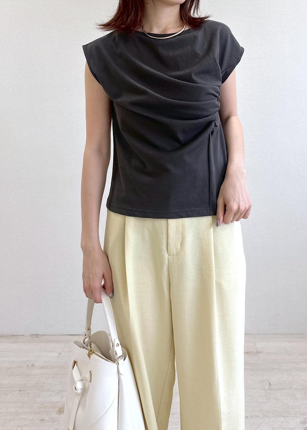 ホワイト系のショルダーバッグ、ブラック系のサンダル、イエロー系のスラックスを着用したレディースの夏コーディネートの5枚目の写真