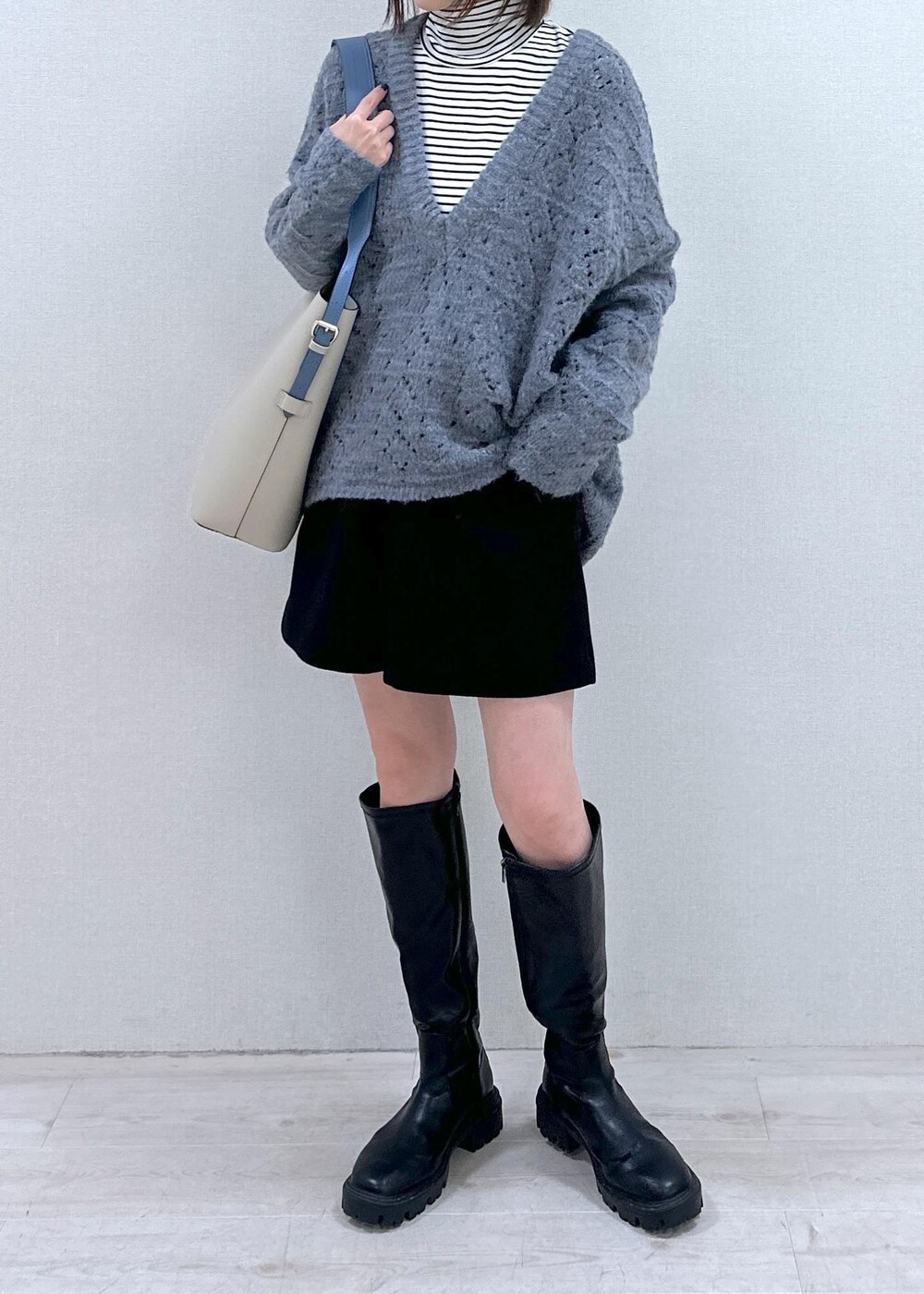 ベージュ系のショルダーバッグ、ブルー系のニット/セーター、ホワイト系のTシャツ/カットソーを着用したレディースの冬コーディネートの4枚目の写真