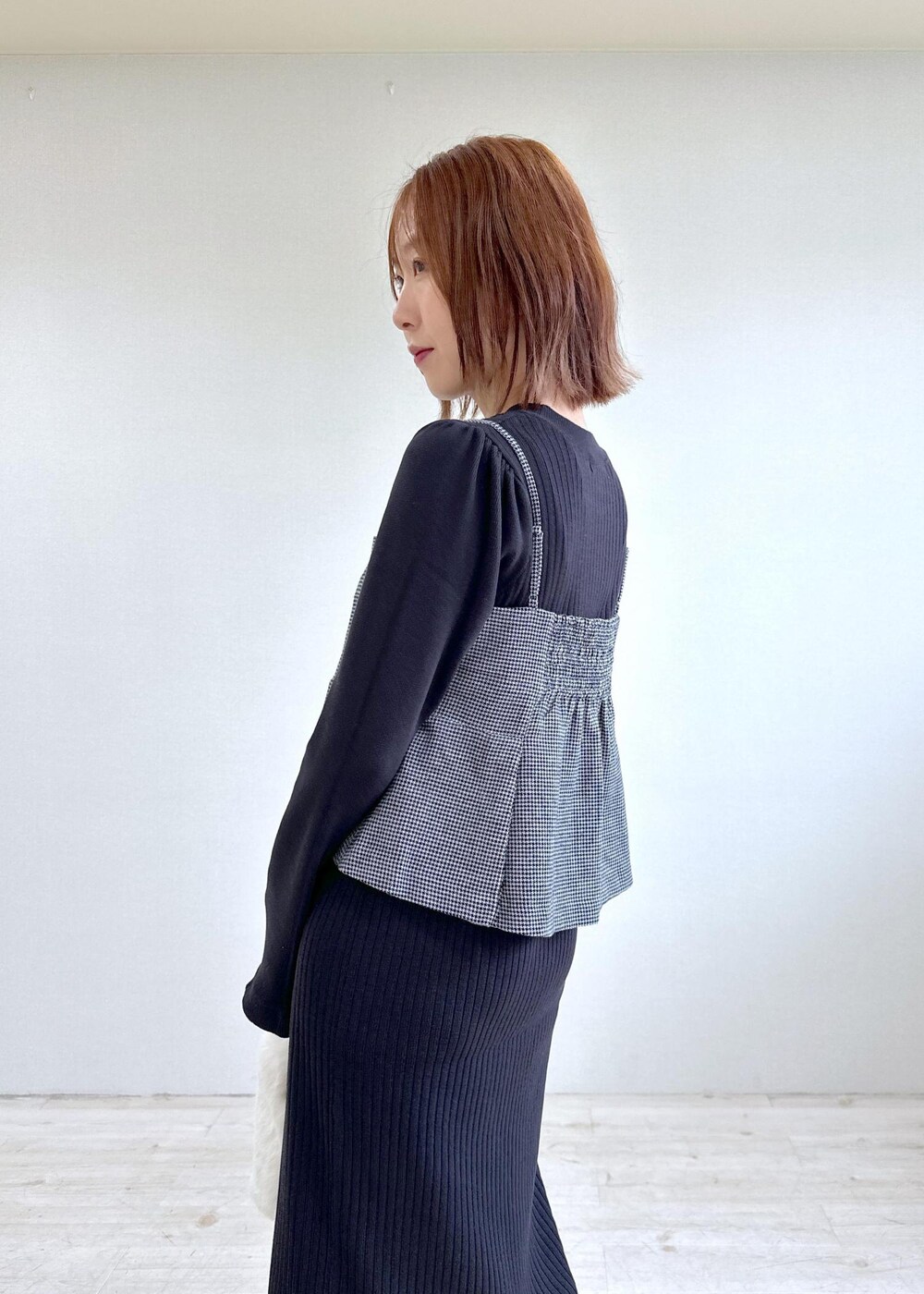 ホワイト系のショルダーバッグ、ホワイト系のブーツ、ブラック系のワンピースを着用したレディースの秋コーディネートの6枚目の写真