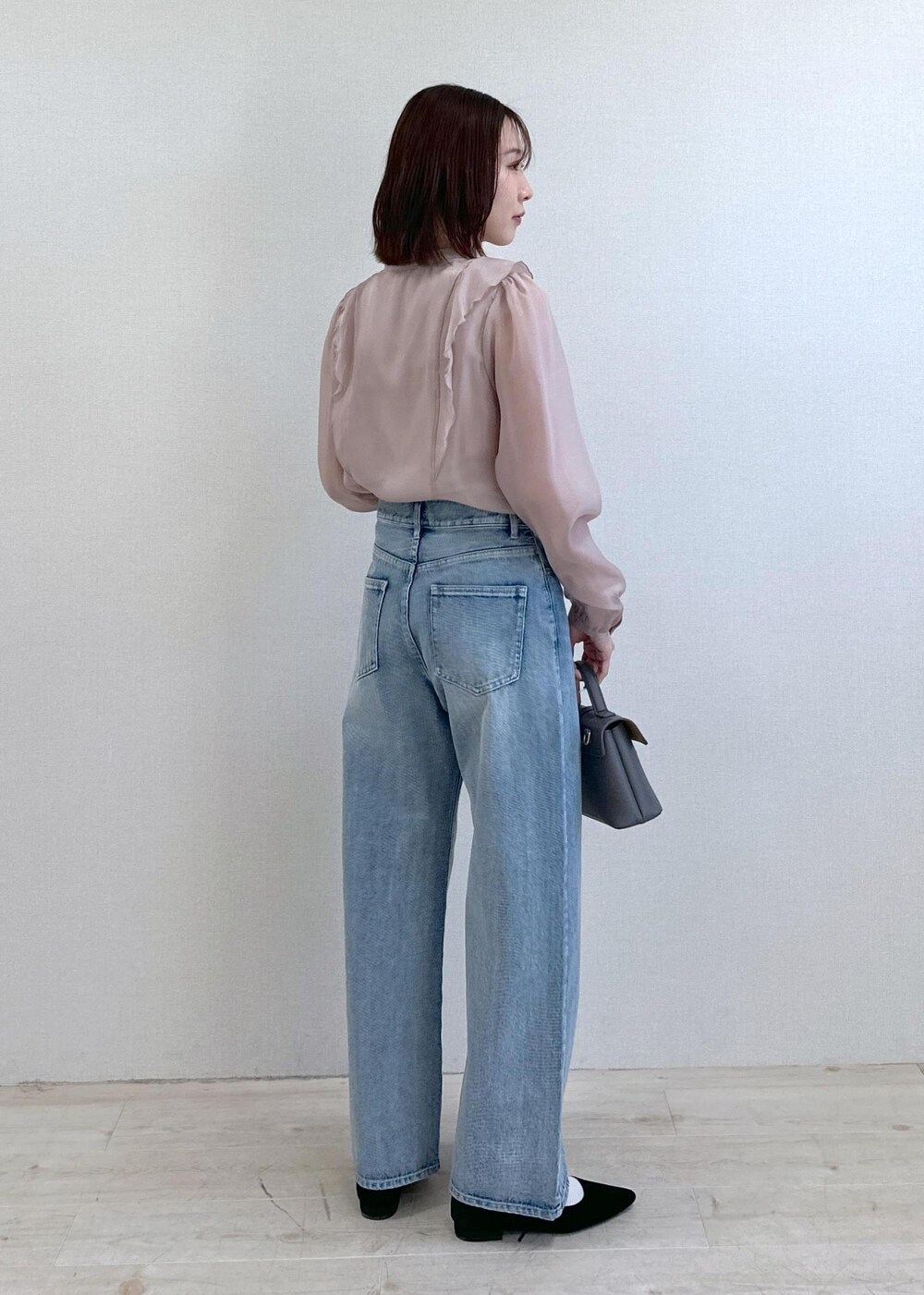 ブルー系のデニムパンツ、ブラック系のパンプス、グレー系のショルダーバッグを着用したレディースの春コーディネートの2枚目の写真