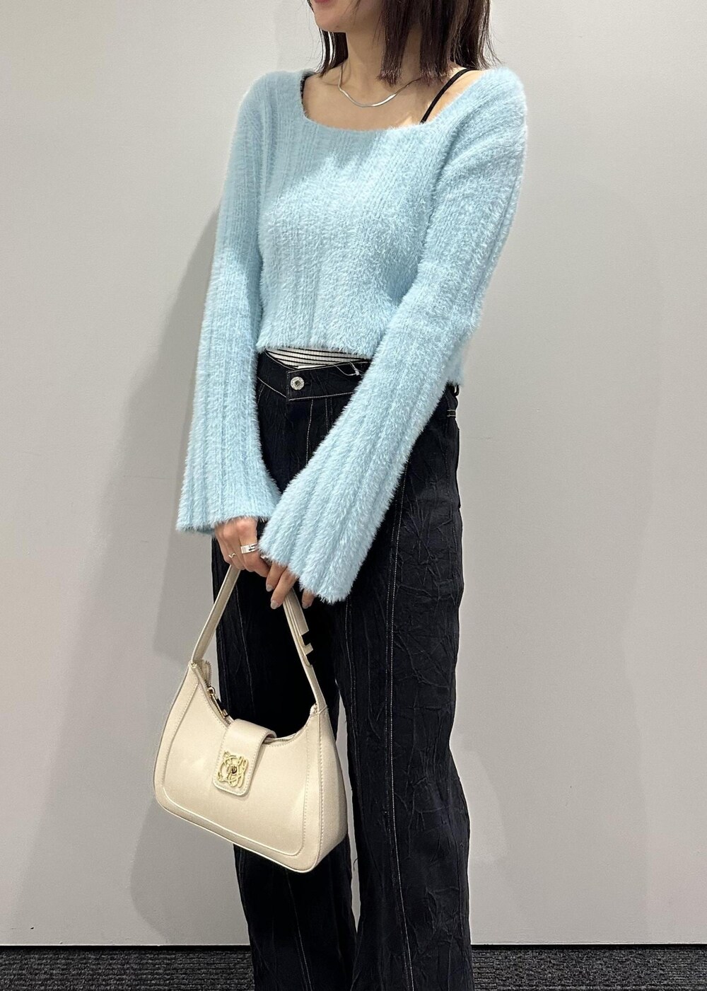ホワイト系のハンドバッグ、シルバー系のその他シューズ、ブルー系のニット/セーターを着用したレディースの冬コーディネートの3枚目の写真