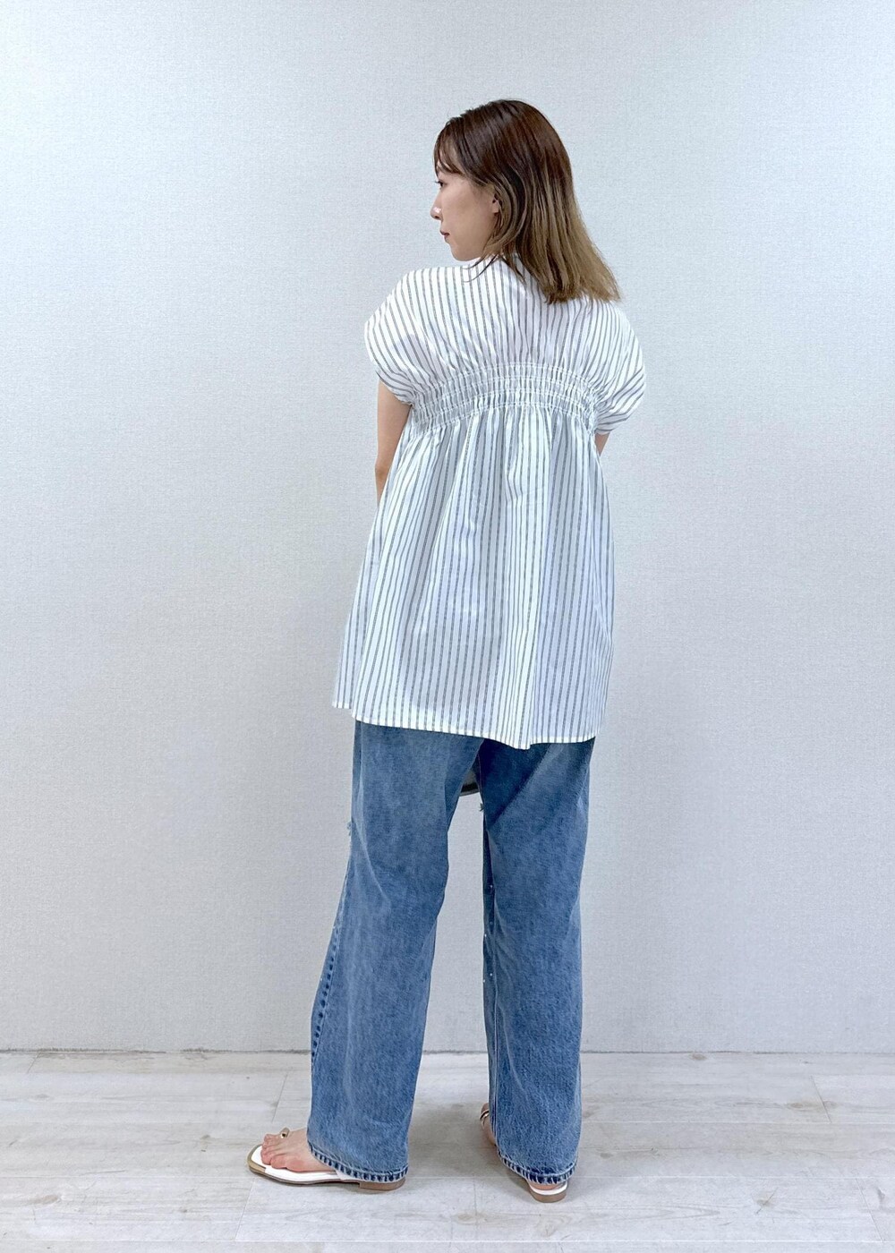 シルバー系のショルダーバッグ、ブルー系のデニムパンツ、ホワイト系のサンダルを着用したレディースの春コーディネートの2枚目の写真