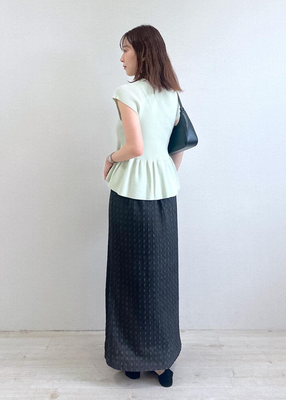 ブラック系のショルダーバッグ、グレー系のスカート、グリーン系のカーディガン/ボレロを着用したレディースの夏コーディネートの2枚目の写真