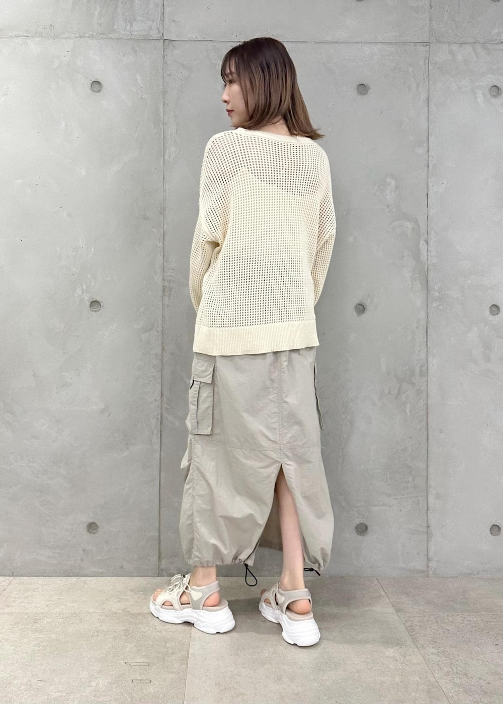 ホワイト系のハンドバッグ、ベージュ系のスカート、ホワイト系のニット/セーターを着用したレディースの春コーディネートの2枚目の写真