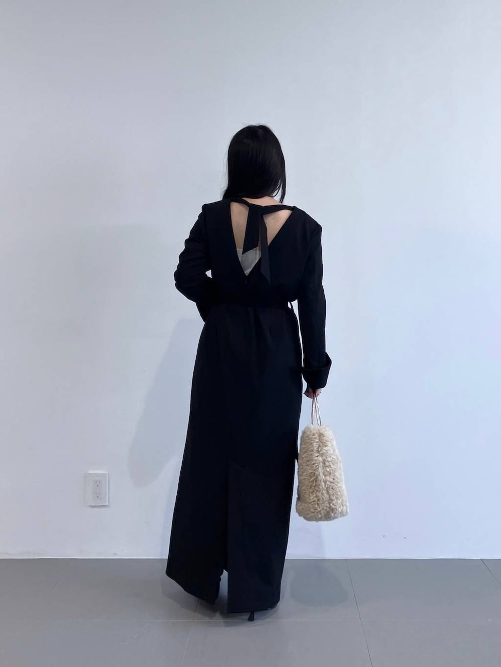 ホワイト系のハンドバッグ、ブラック系のワンピースを着用したレディースの秋コーディネートの5枚目の写真