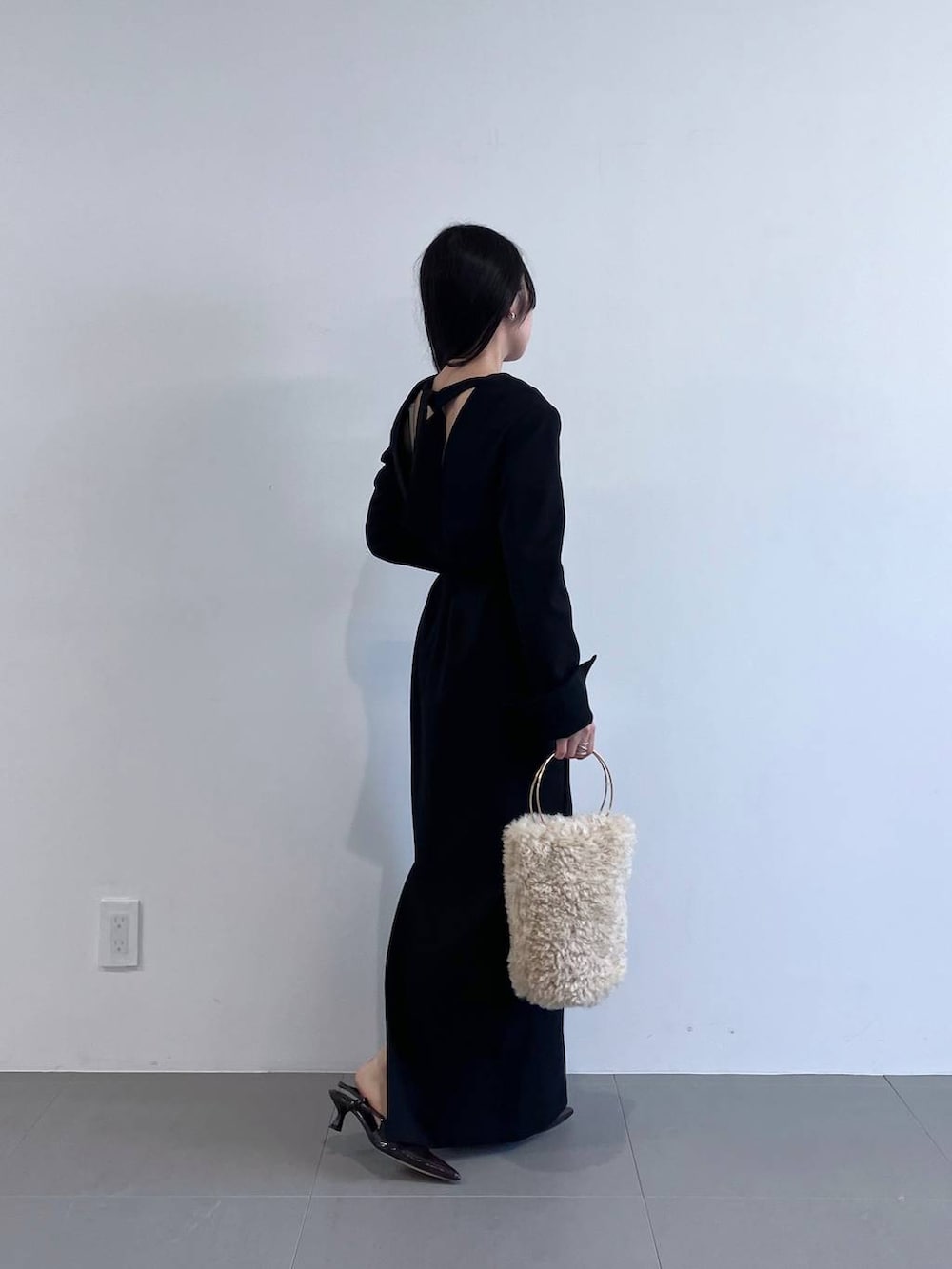 ホワイト系のハンドバッグ、ブラック系のワンピースを着用したレディースの秋コーディネートの4枚目の写真