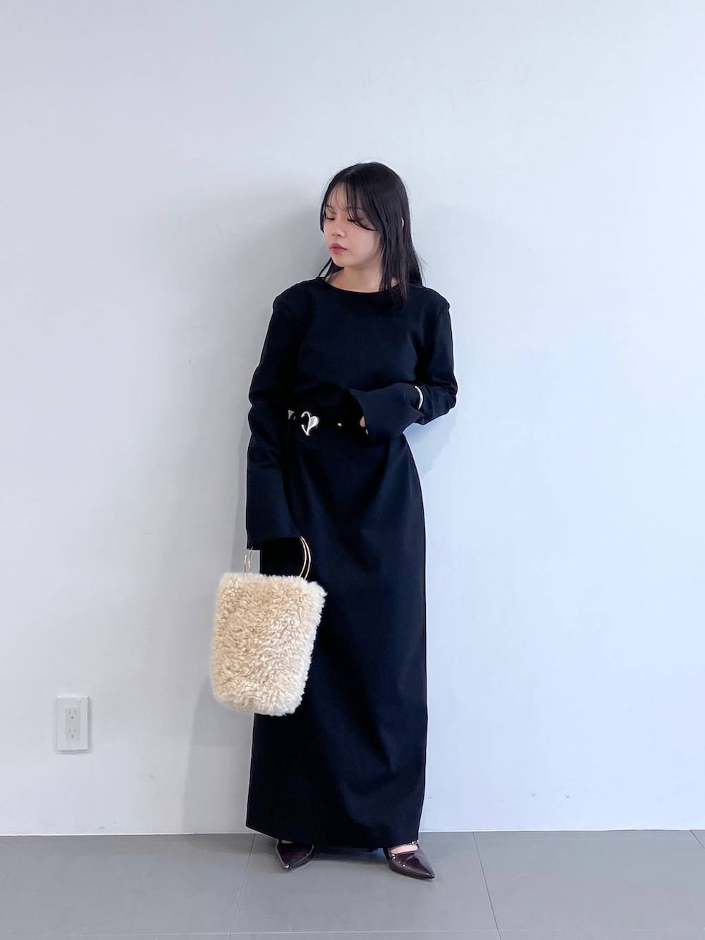 ホワイト系のハンドバッグ、ブラック系のワンピースを着用したレディースの秋コーディネートの6枚目の写真