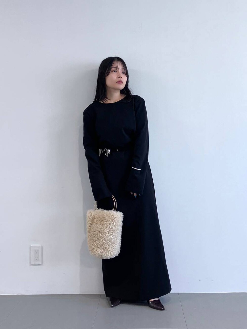 ホワイト系のハンドバッグ、ブラック系のワンピースを着用したレディースの秋コーディネートの7枚目の写真