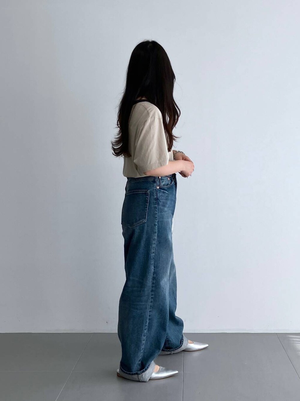 ブルー系のデニムパンツ、シルバー系のパンプス、ベージュ系のTシャツ/カットソーを着用したレディースの夏コーディネートの3枚目の写真